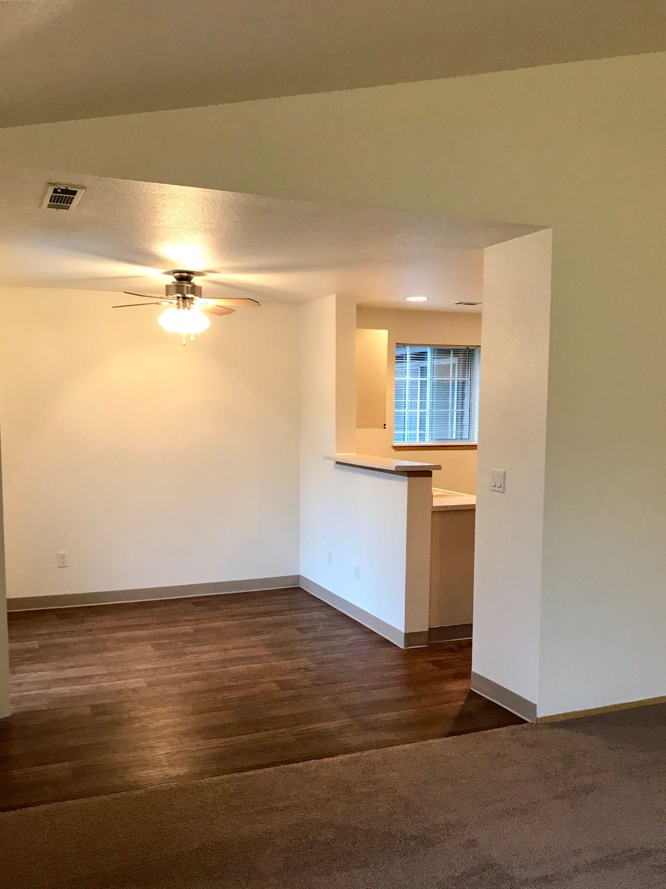 An empty living room with hardwood floors and a ceiling fan.