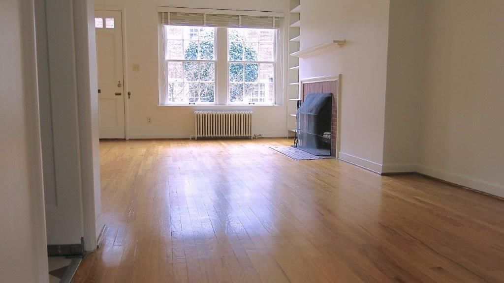 An empty living room with hardwood floors and a fireplace
