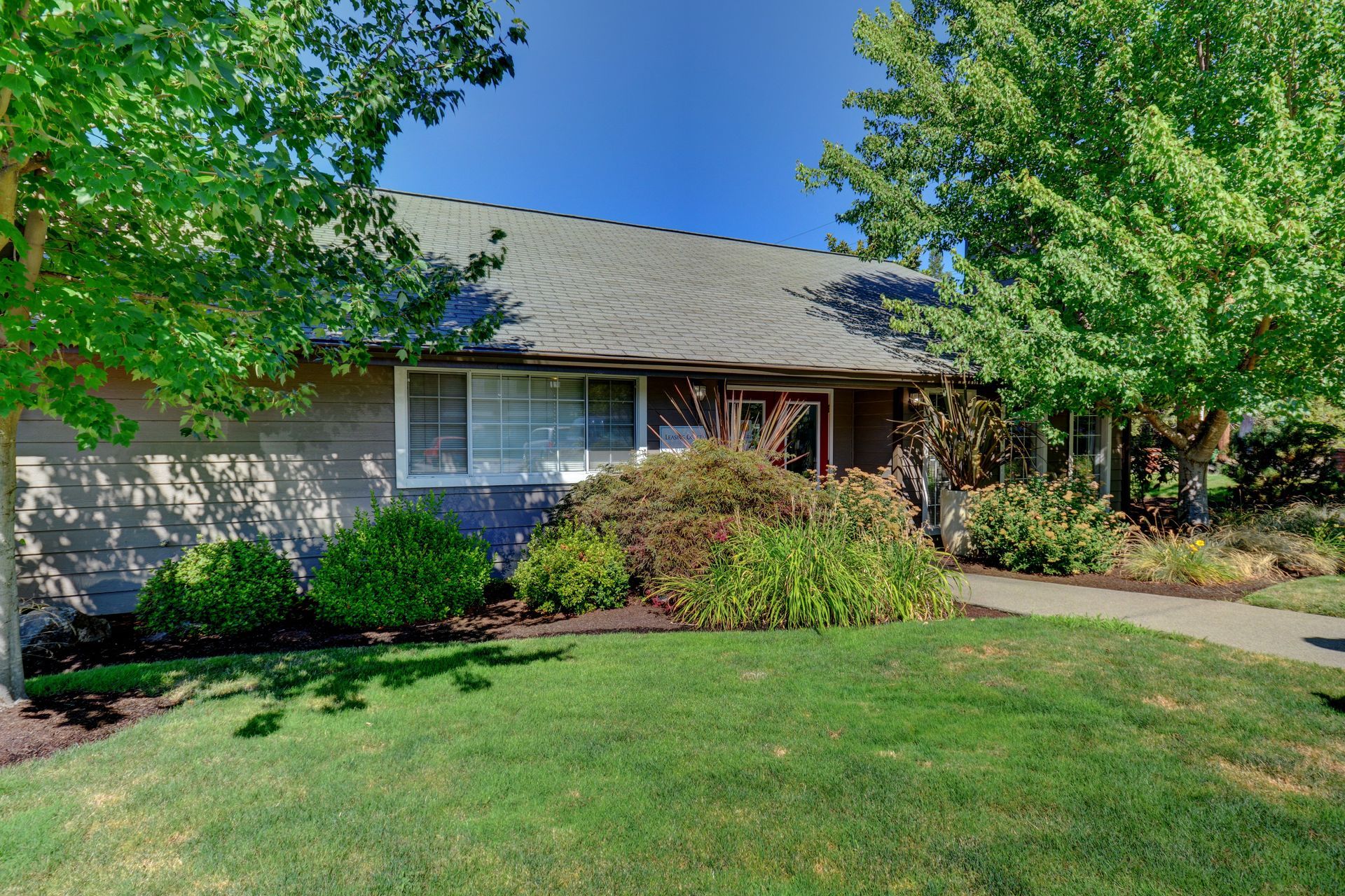 A house with a large lawn and trees in front of it