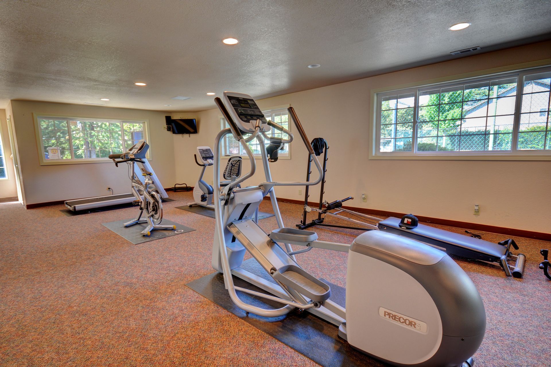A gym with a treadmill , elliptical , and other exercise equipment.