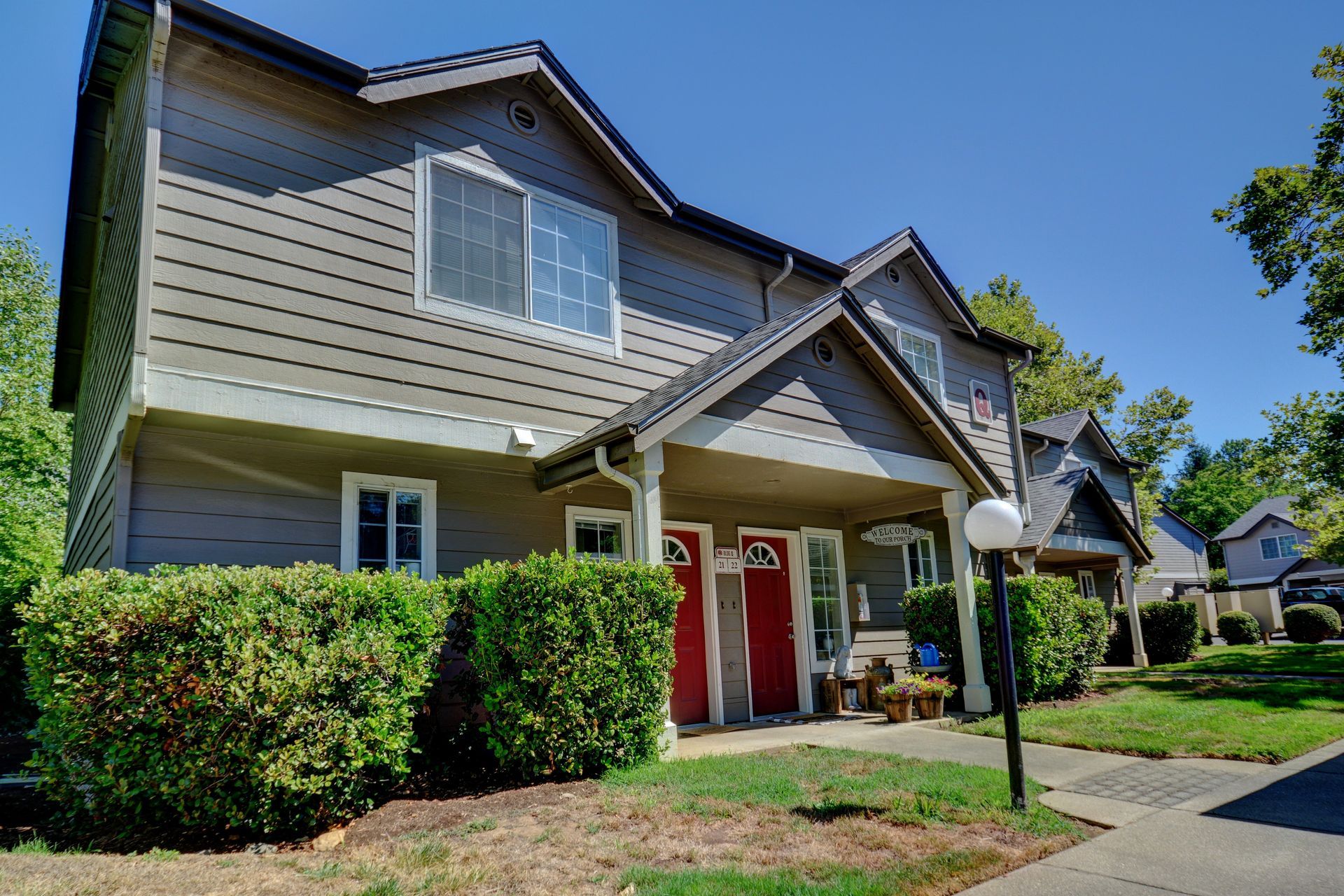 A house with a red door is surrounded by trees and bushes.