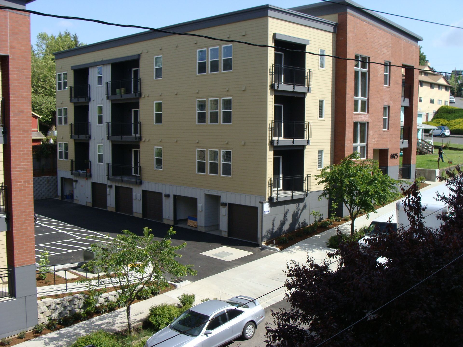 A white car is parked in front of a large apartment building