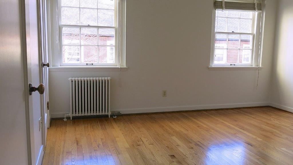 An empty room with hardwood floors and two windows.