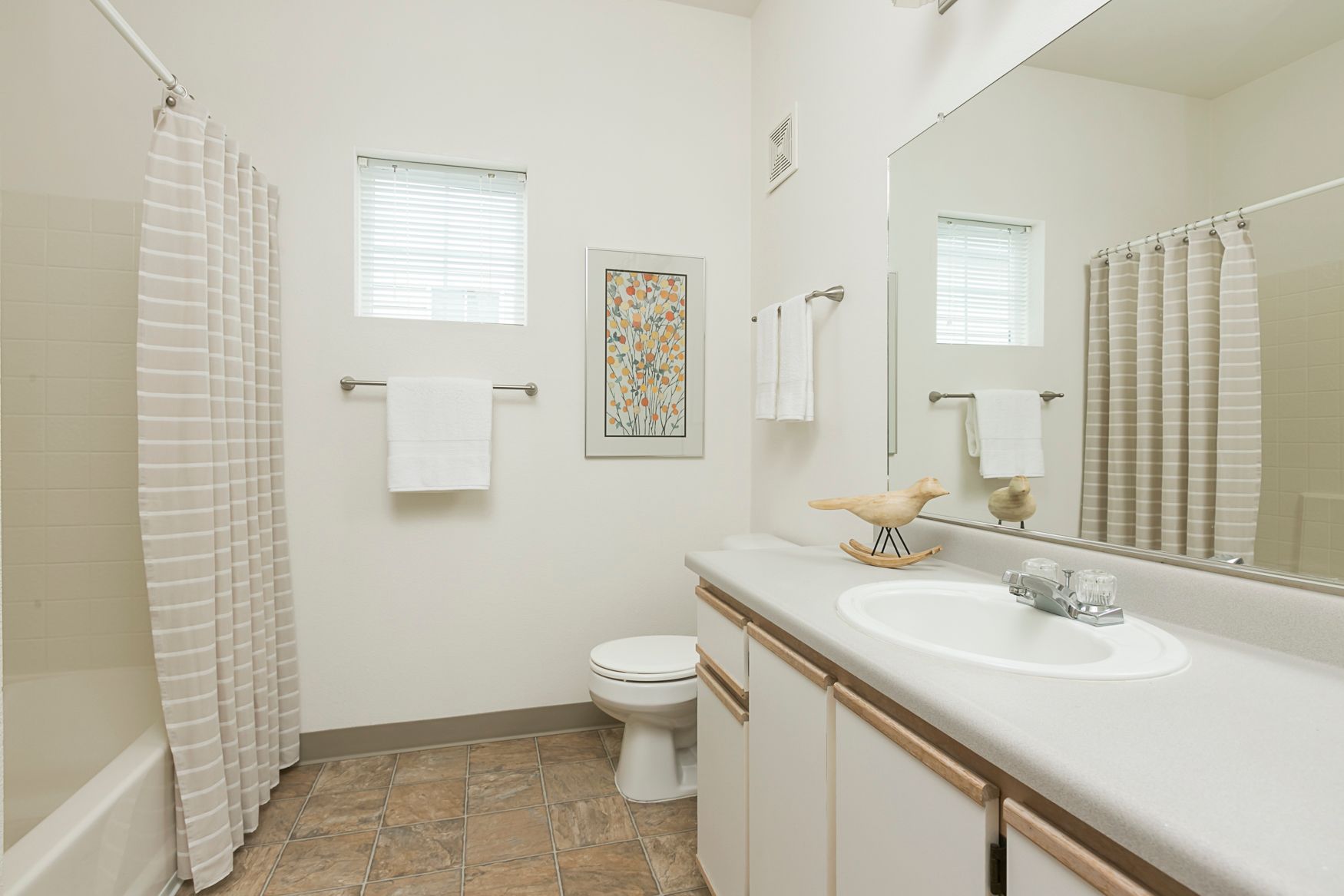 A bathroom with a sink , toilet , shower and mirror.