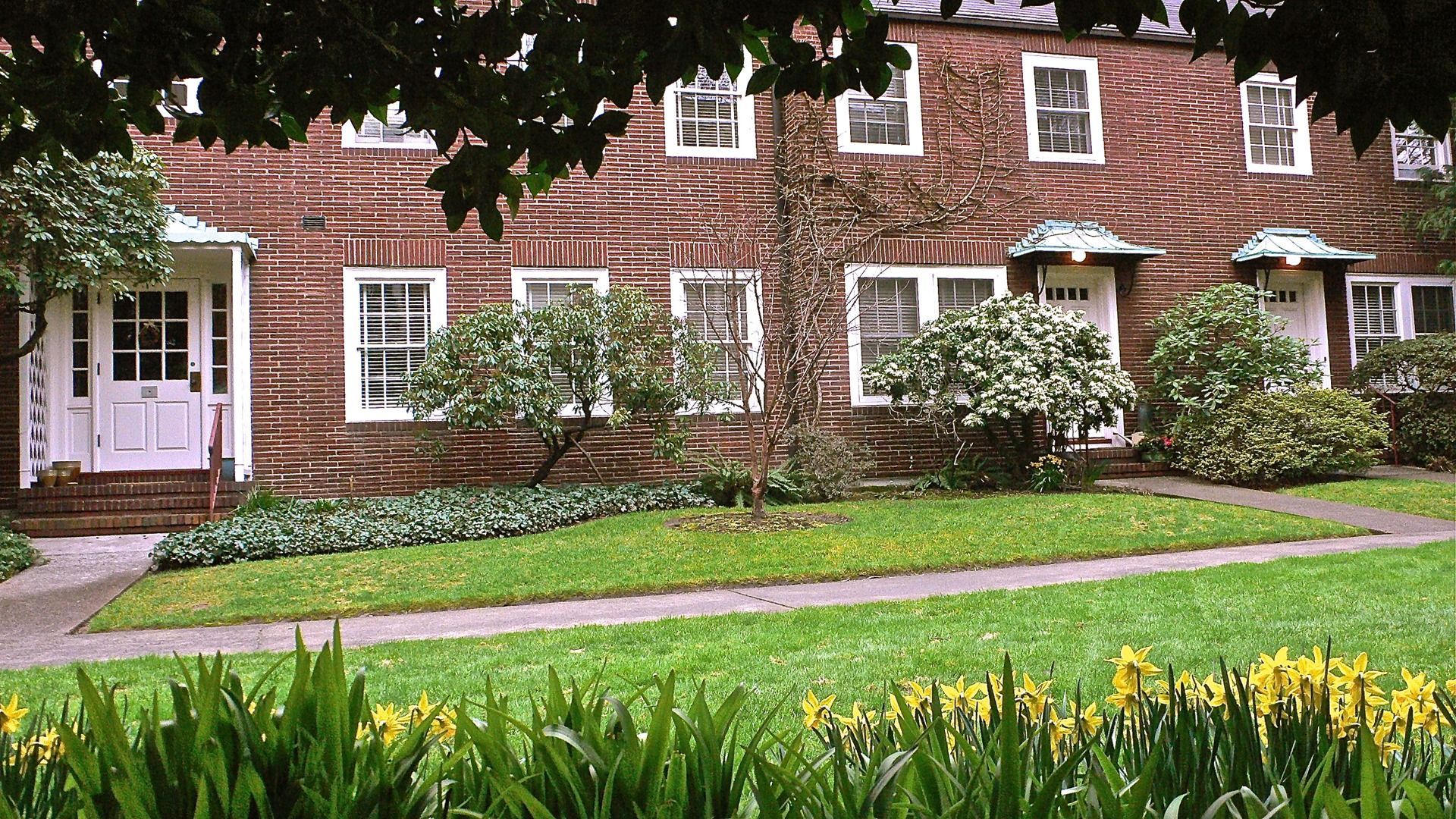 A large brick building with a lush green lawn in front of it