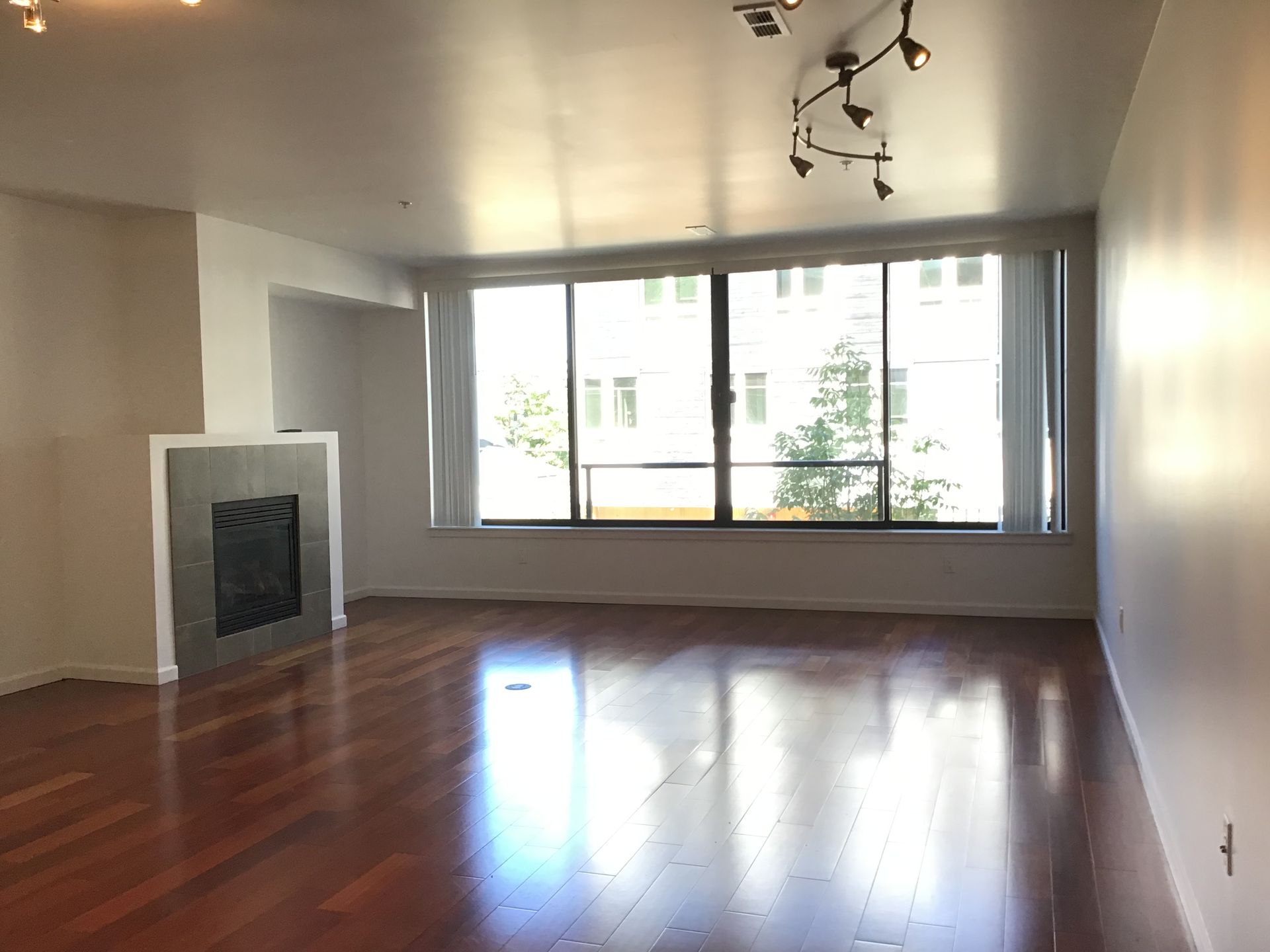 An empty living room with hardwood floors and a fireplace