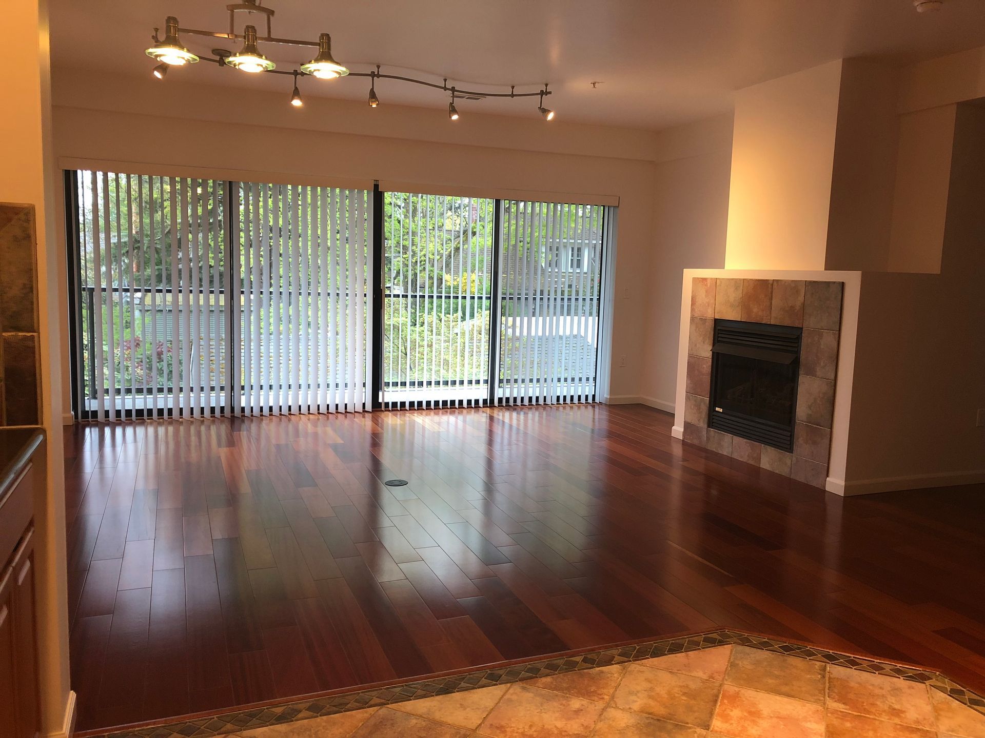 An empty living room with hardwood floors and a fireplace.
