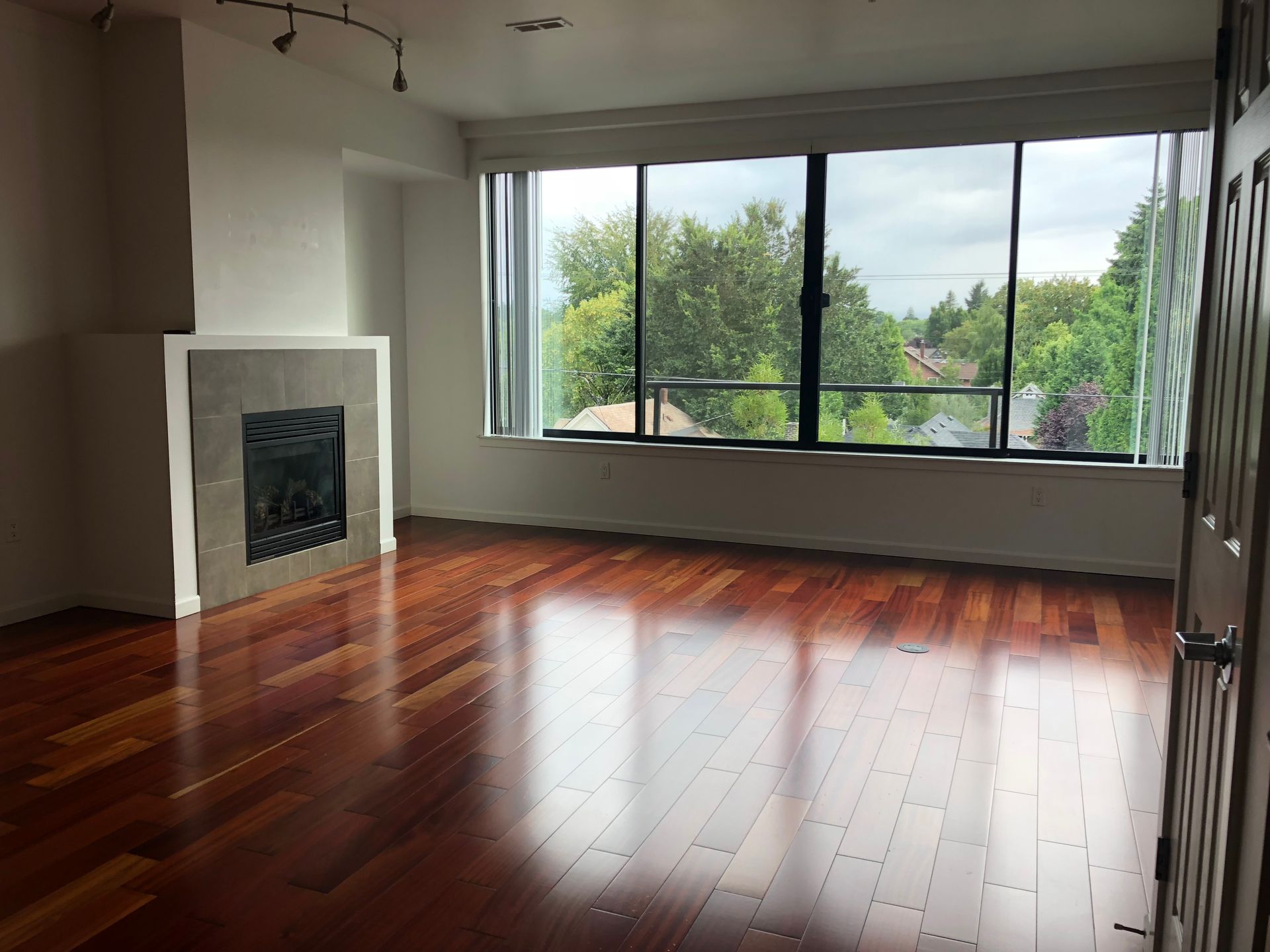 An empty living room with hardwood floors and a fireplace.