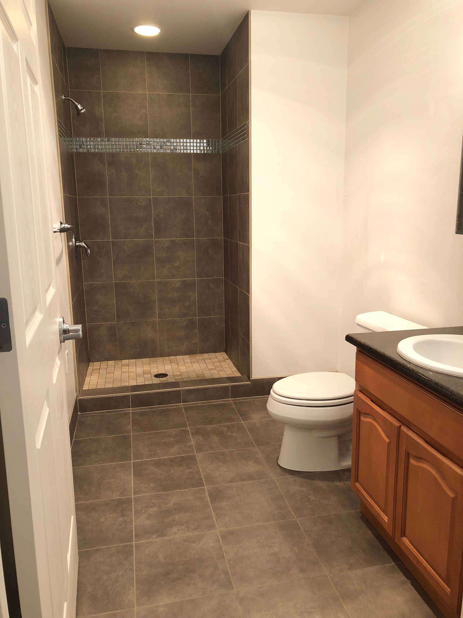 A bathroom with a toilet , sink and shower.