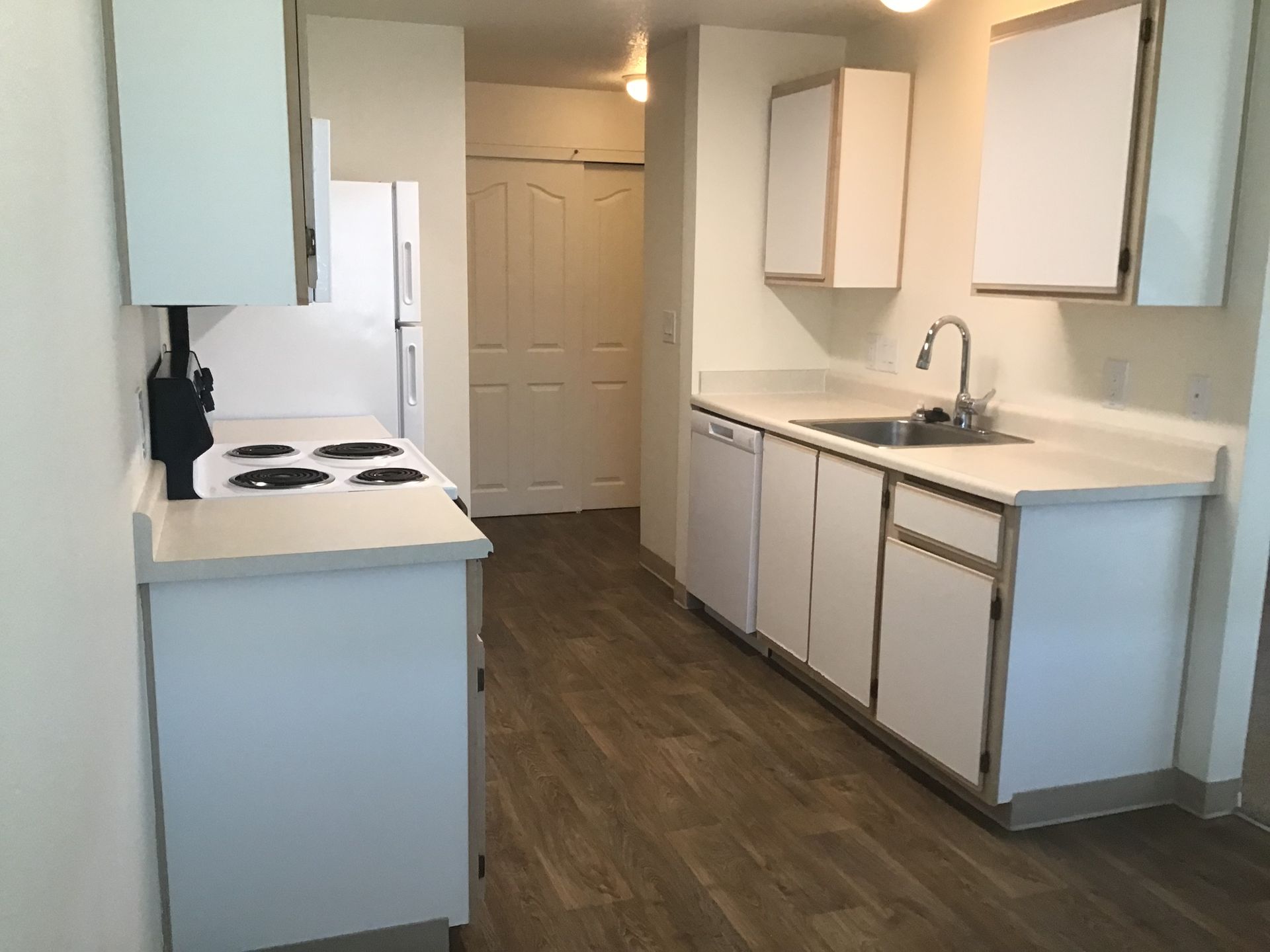 An empty kitchen with white cabinets and a sink