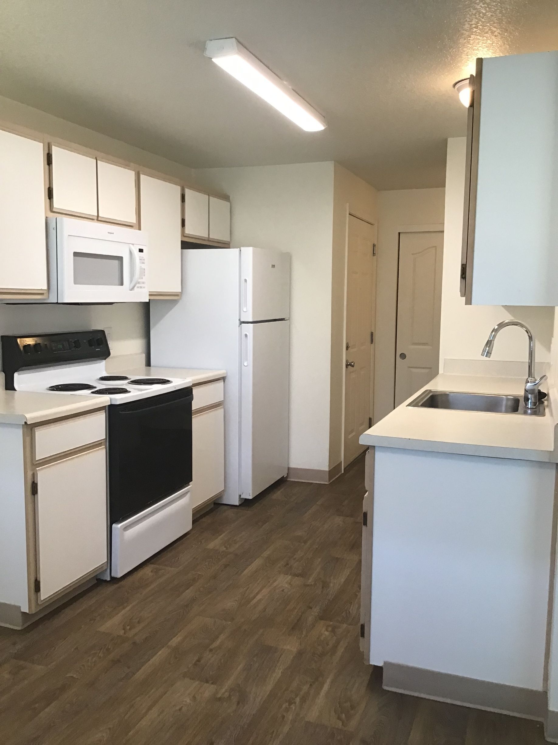 A kitchen with white cabinets a stove a refrigerator and a sink