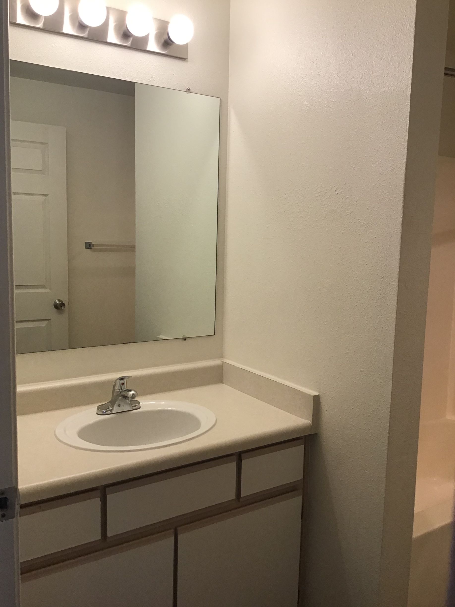 A bathroom with a sink , mirror and lights.