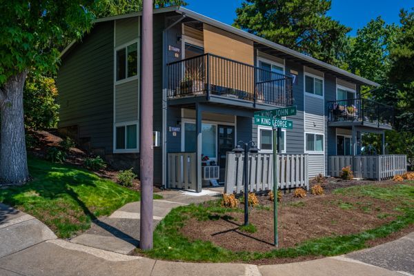 A large apartment building with a balcony and a sidewalk in front of it.