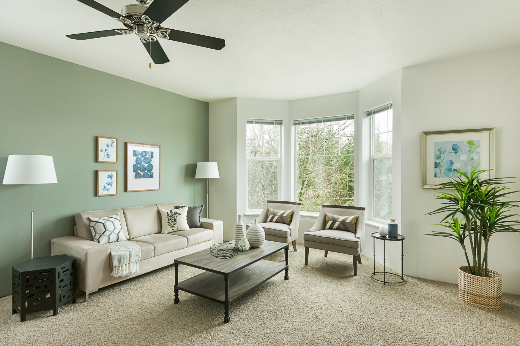 A living room with a couch , chairs , coffee table and ceiling fan.