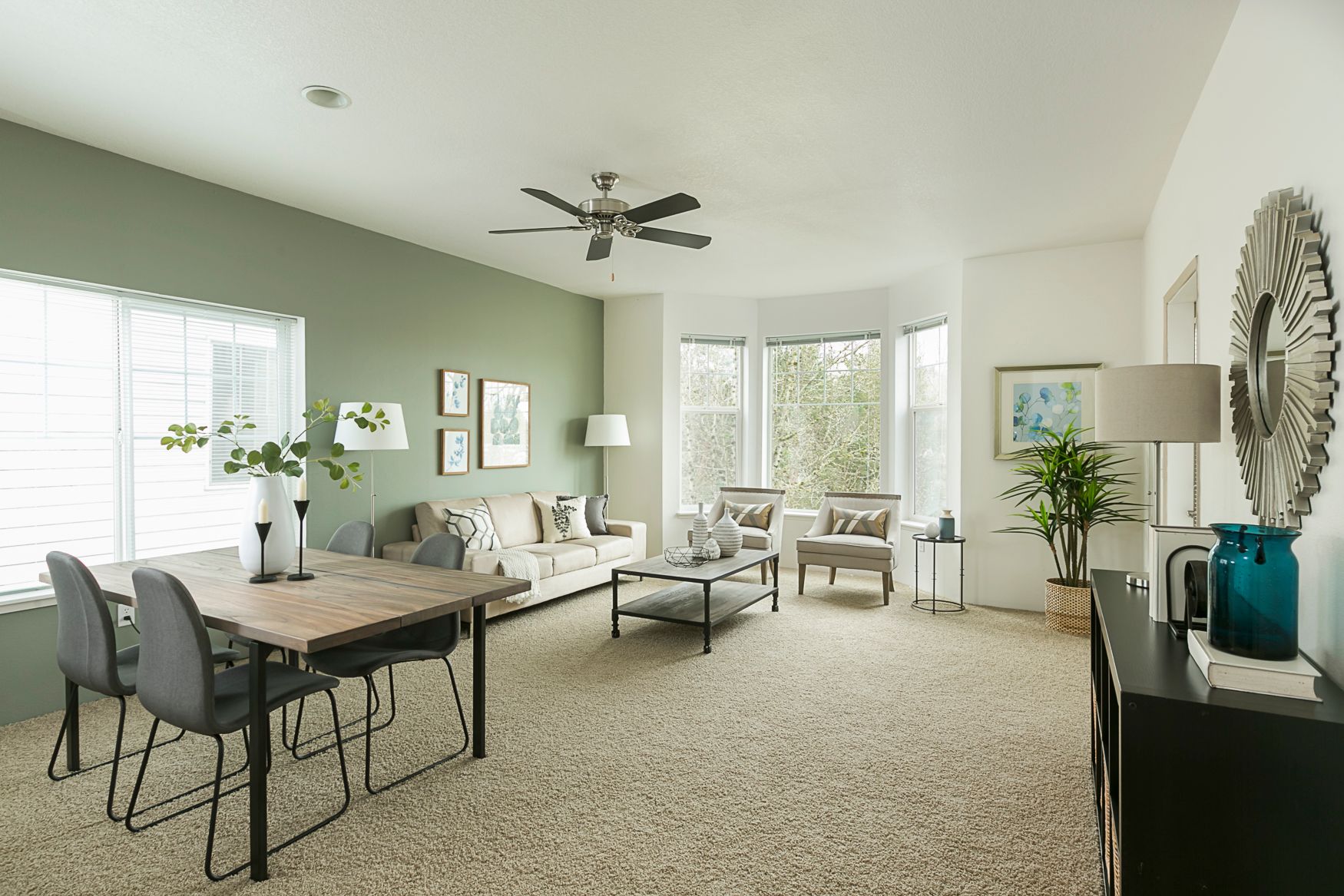 A living room with a table and chairs and a ceiling fan.