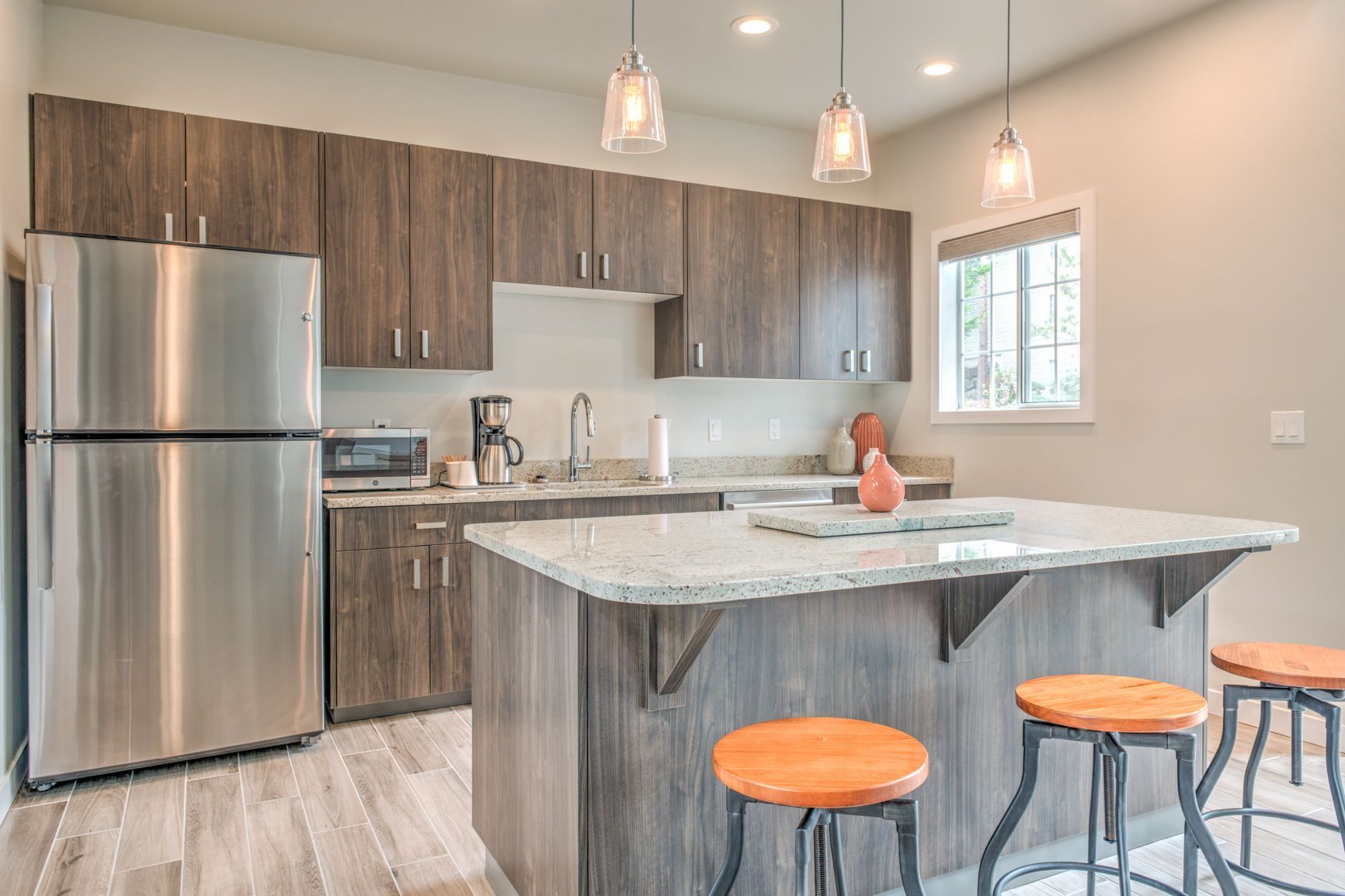 A kitchen with stainless steel appliances , wooden cabinets , granite counter tops , and a large island.