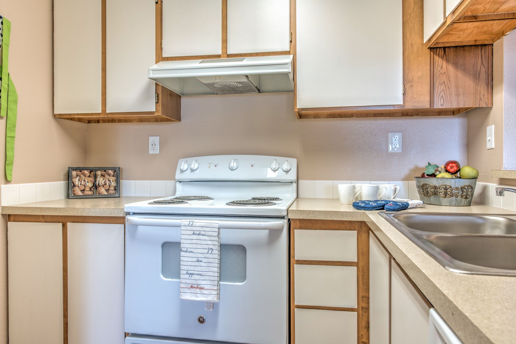 A kitchen with a stove , sink , and cabinets.