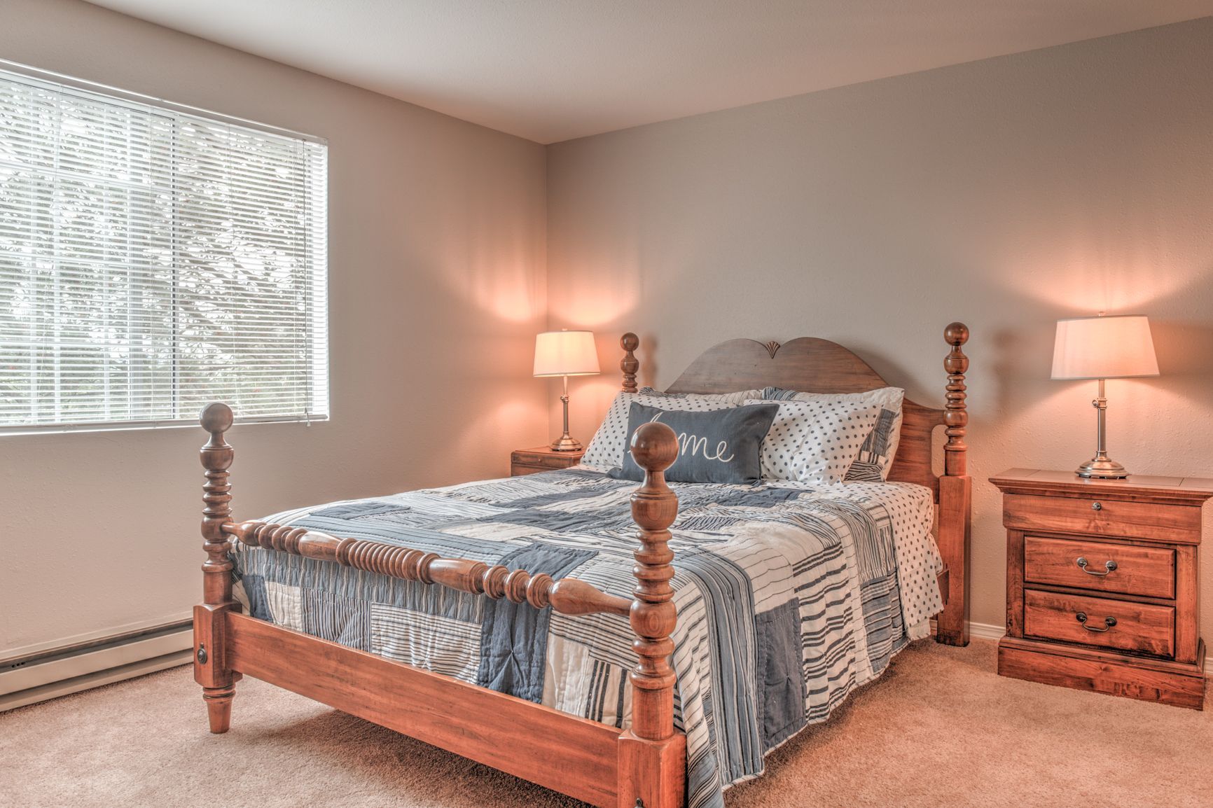 A bedroom with a bed , nightstand , lamps and a window.