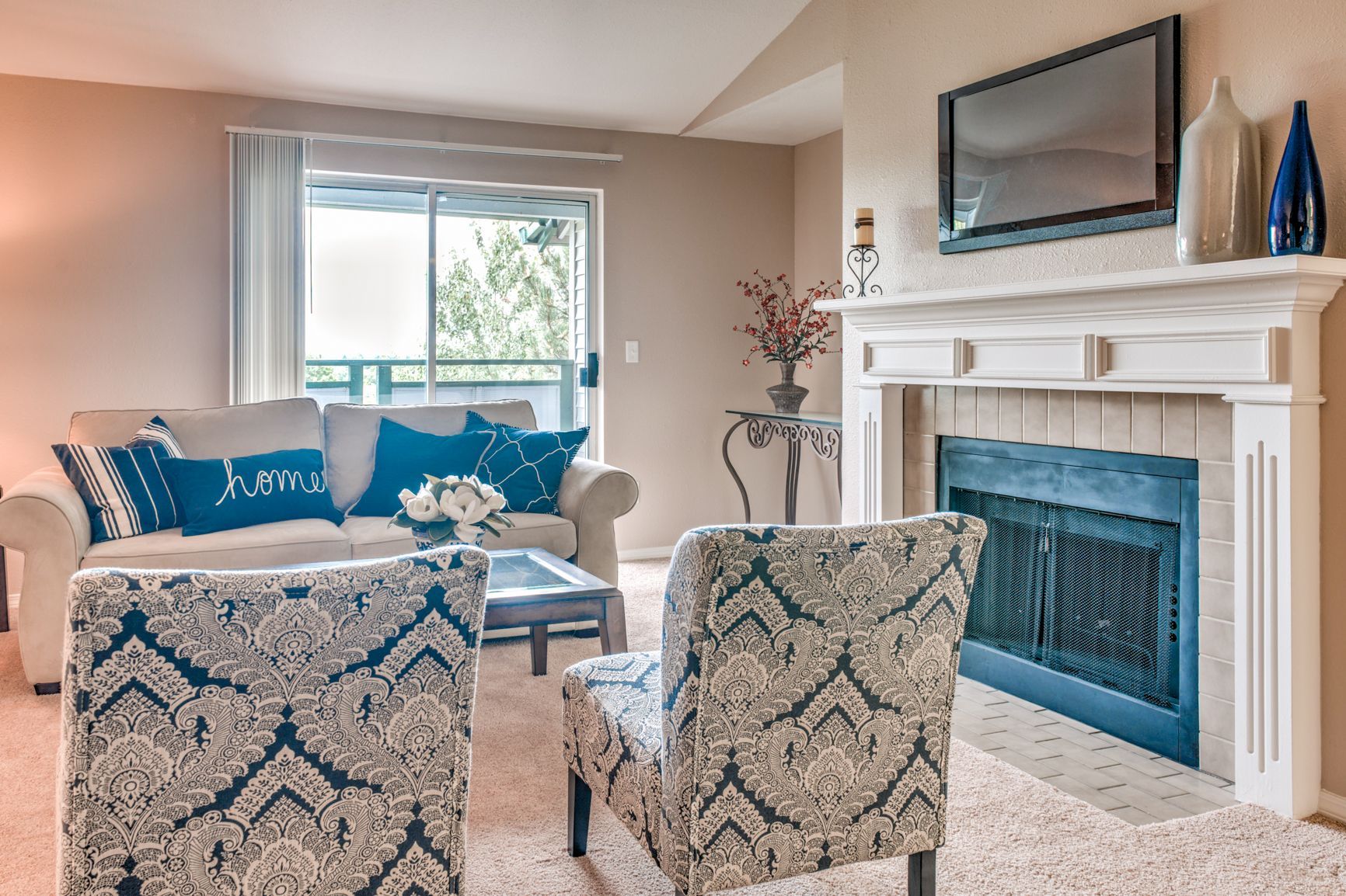 A living room with a couch , chairs , fireplace and television.