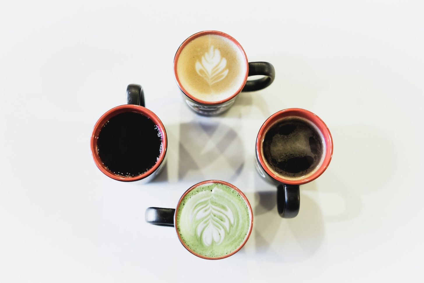 Four cups of coffee are sitting in a circle on a table.