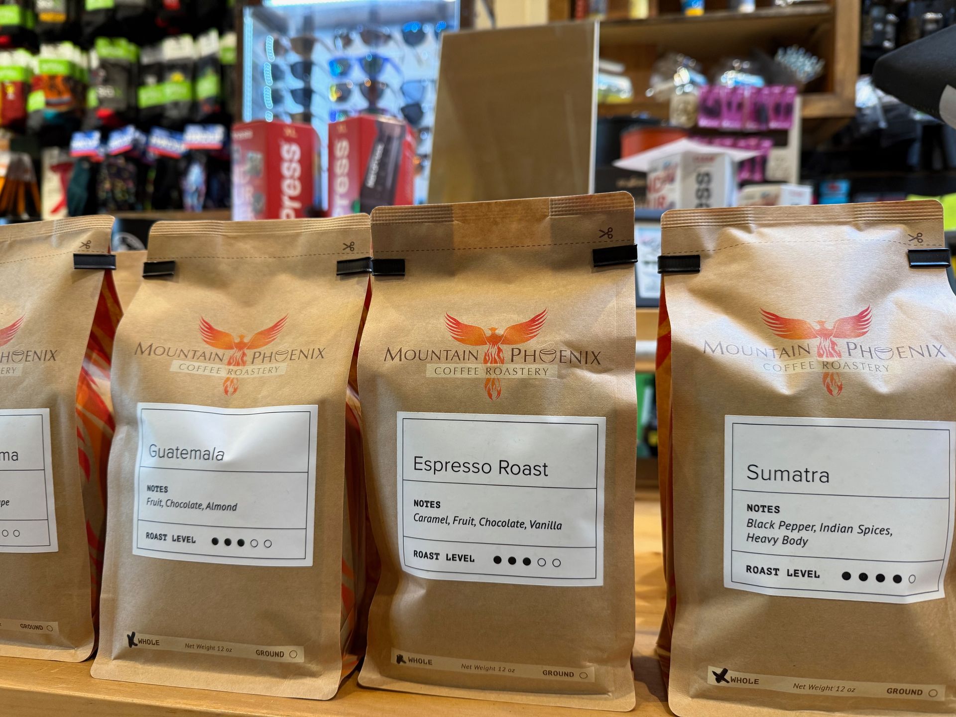 Four bags of coffee are lined up on a shelf in a store.