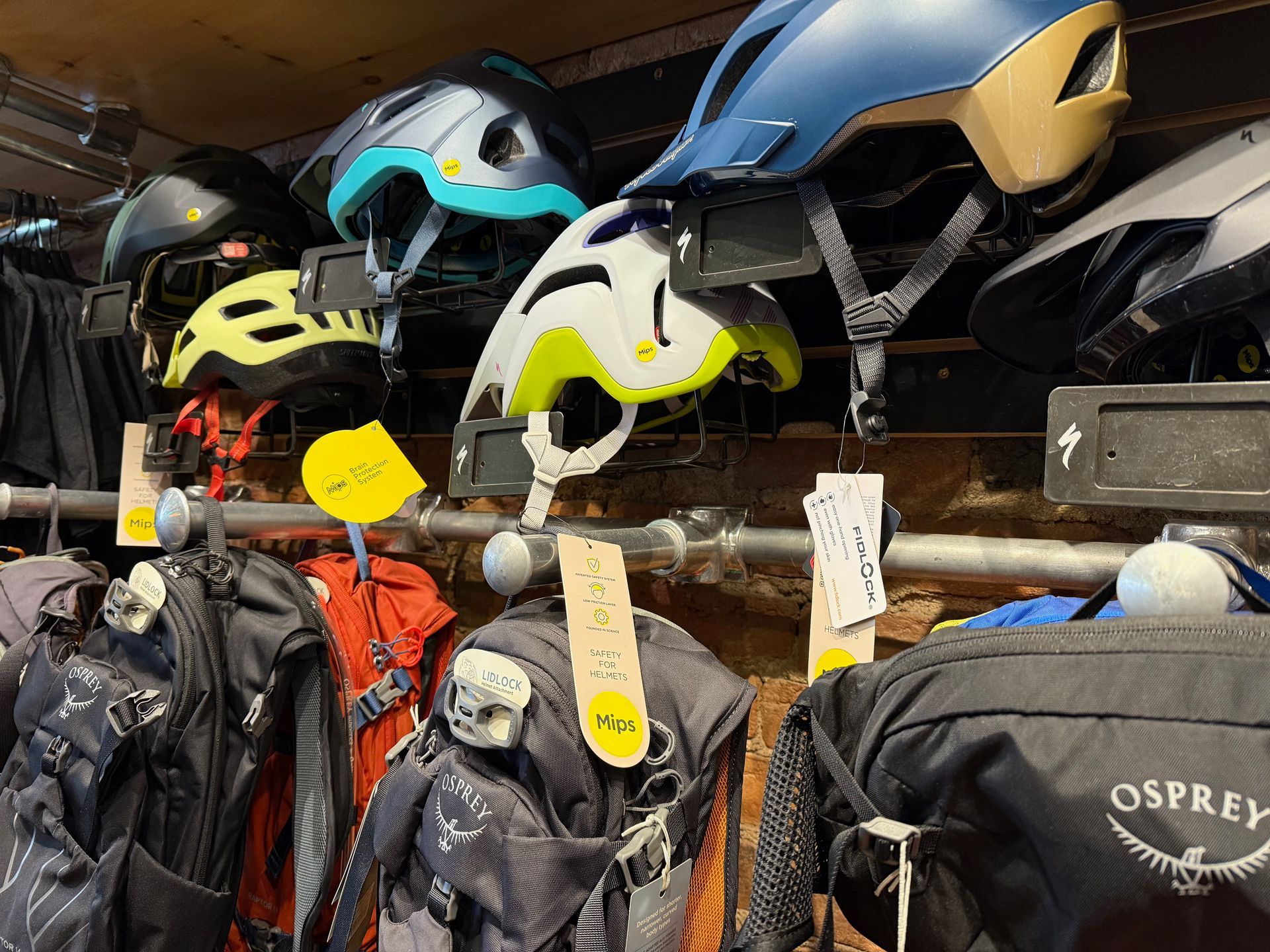 A bunch of helmets are hanging on a rack in a store.