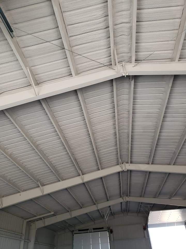 White metal industrial building ceiling with beams and corrugated panels.