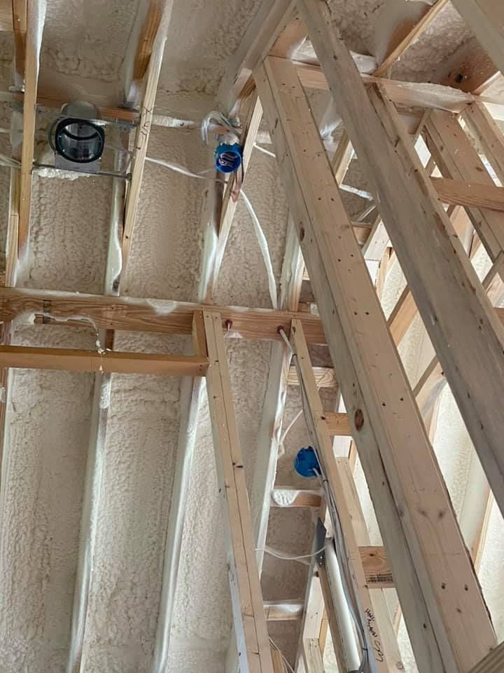 Interior view of a new construction attic with spray foam insulation, framing, and electrical boxes.