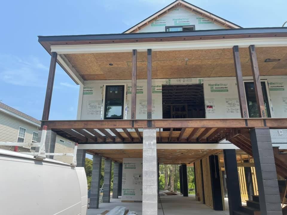 New house under construction with a raised foundation, unfinished, with steel beams and posts.