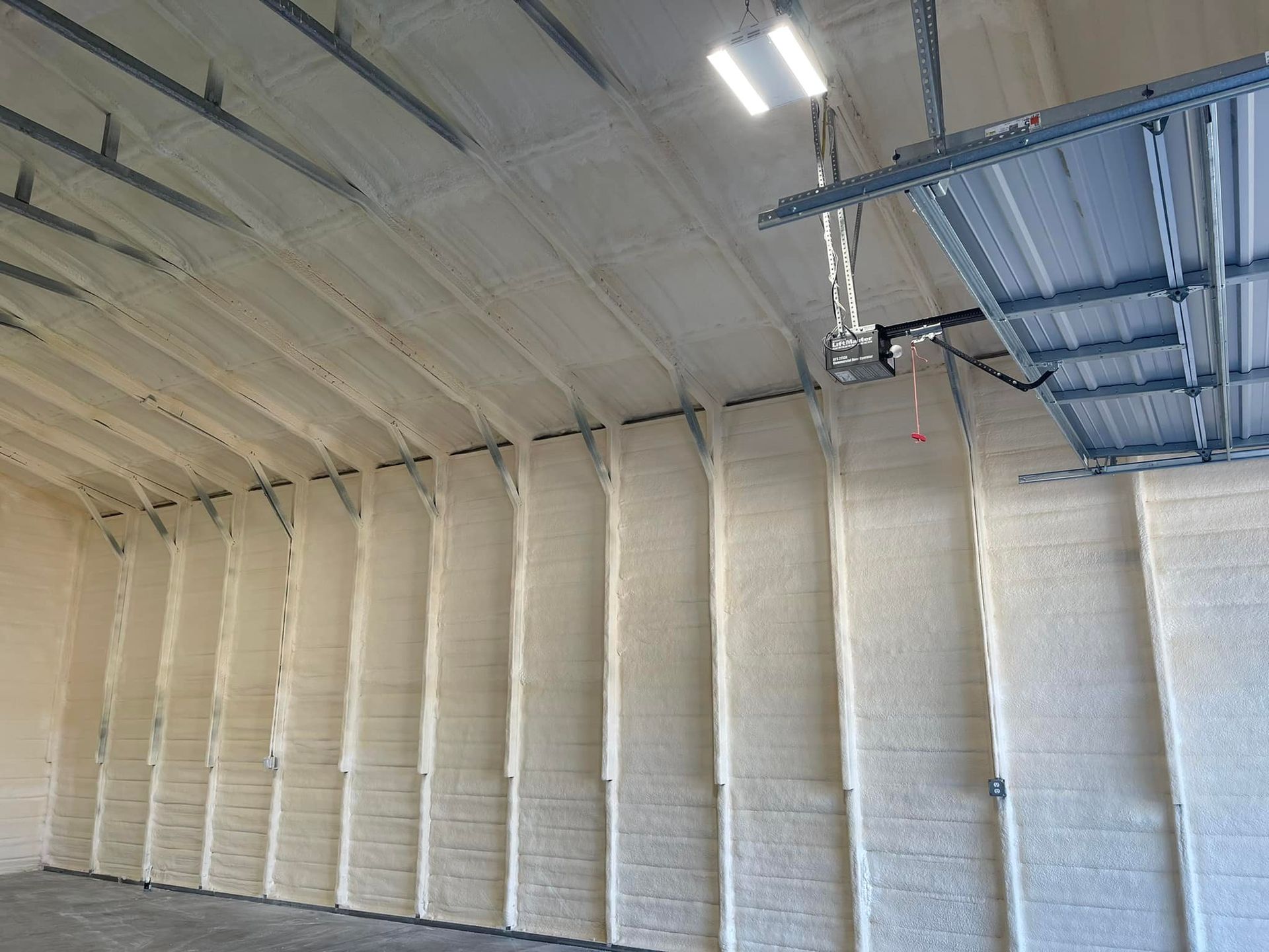 Garage interior with beige spray foam insulation on walls and ceiling.