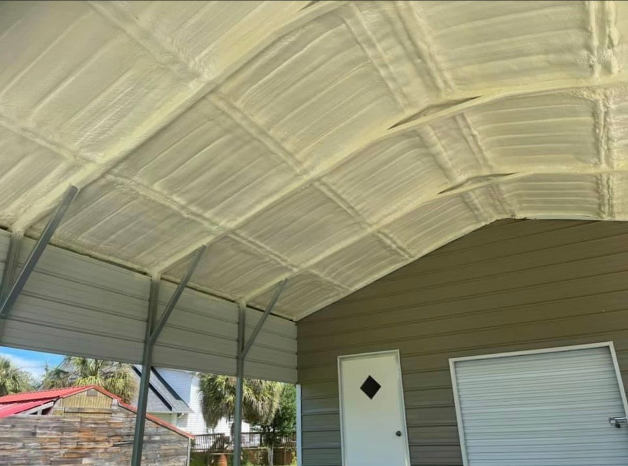 Insulated carport ceiling with visible metal beams. Beige spray foam insulation, gray metal frame, light tan siding.