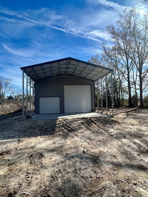 Gray metal building with two white garage doors, under a blue sky.