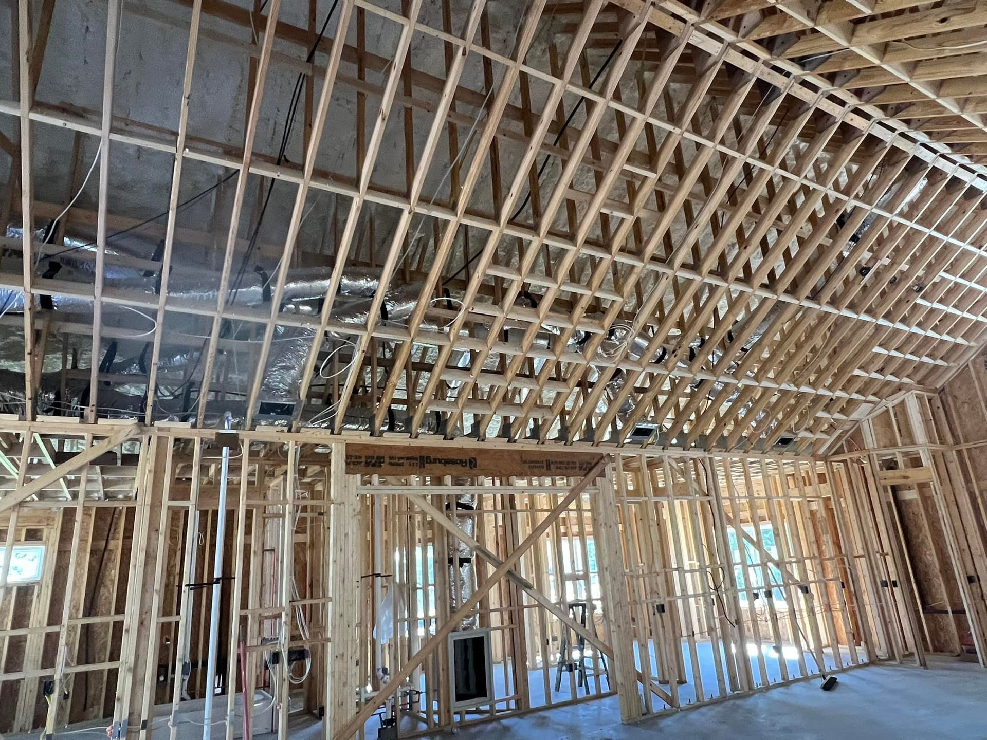 Interior view of a building under construction, showing wooden framing for walls and sloped ceiling.