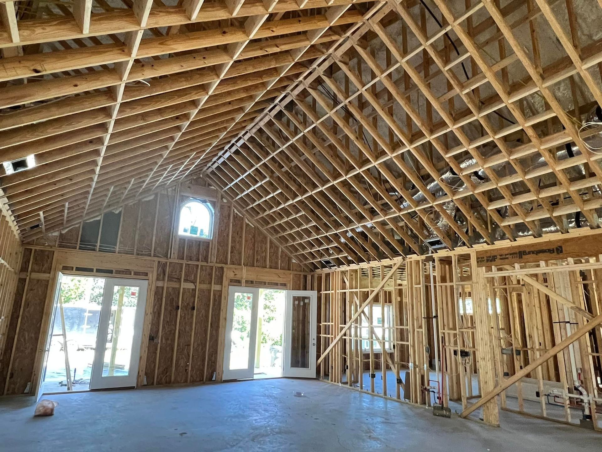 Interior view of a building under construction, showing wooden framing for walls and ceiling, including doors and windows.