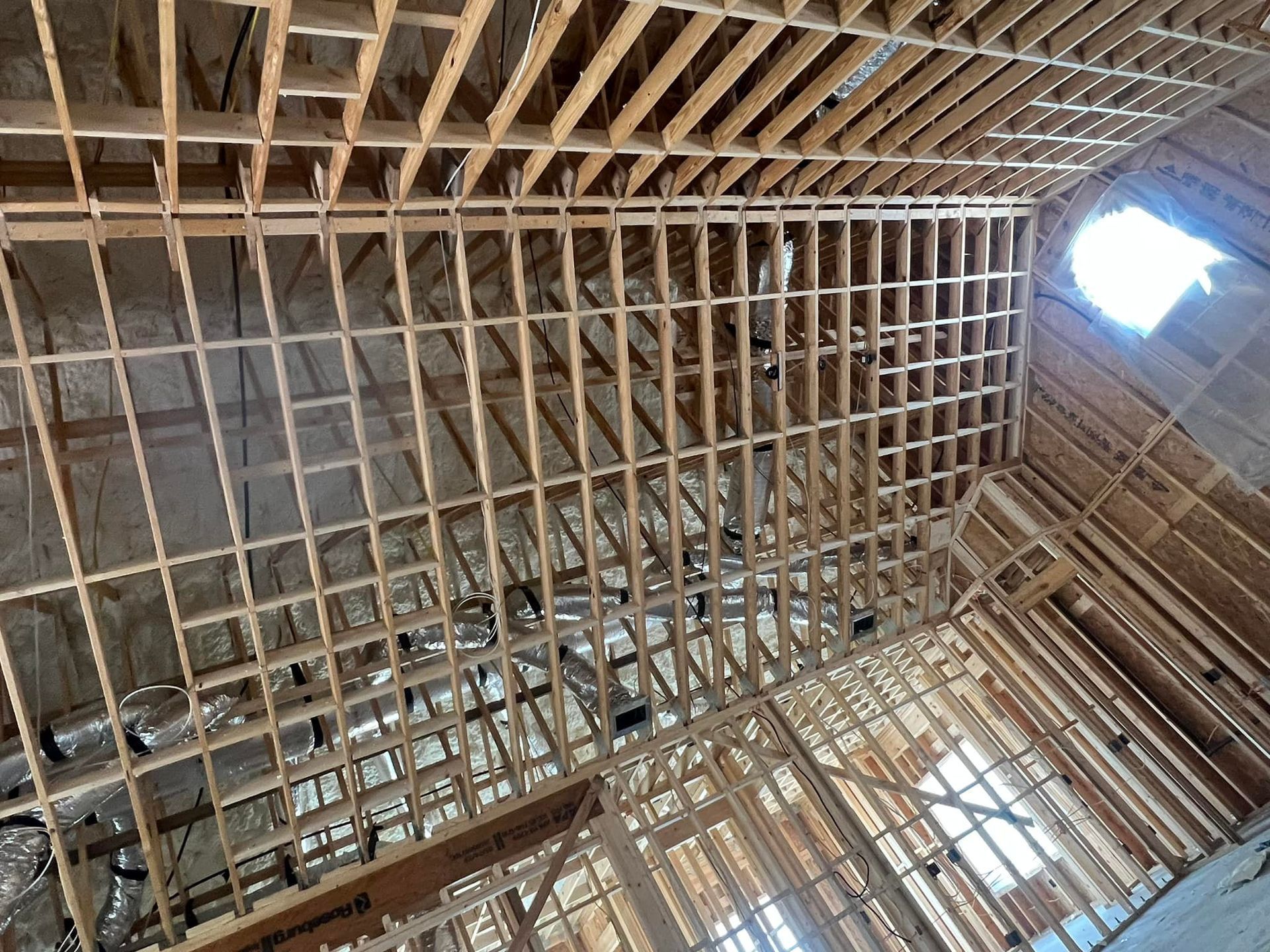 Interior view of a building under construction, showing wooden framing for walls and ceiling, with insulation visible.