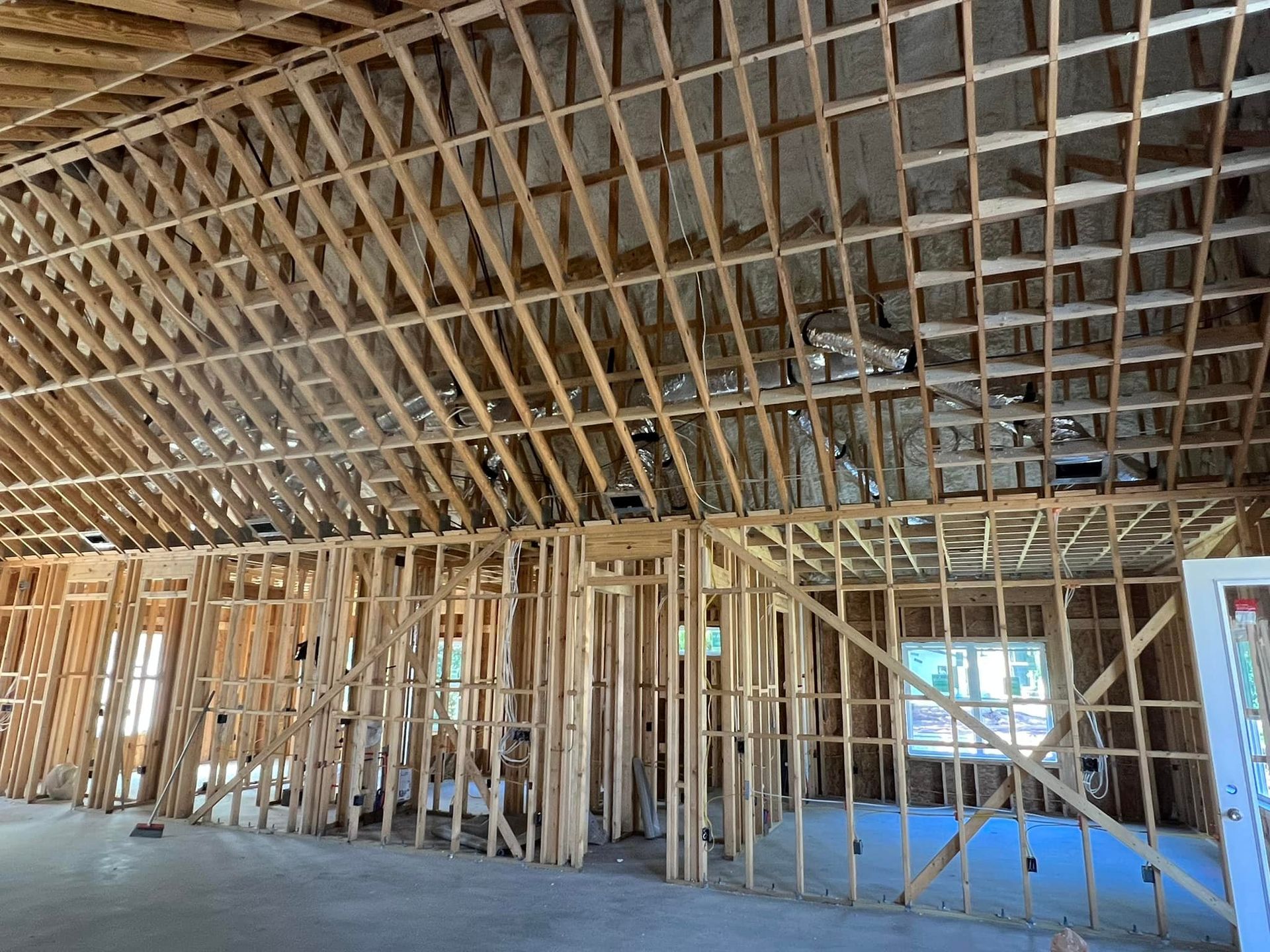 Interior view of a building under construction, showing exposed wooden framing for walls and ceiling.