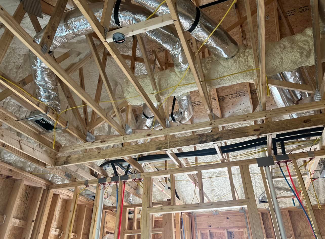 Wooden framing of a room under construction with HVAC ductwork, pipes, and wiring visible.