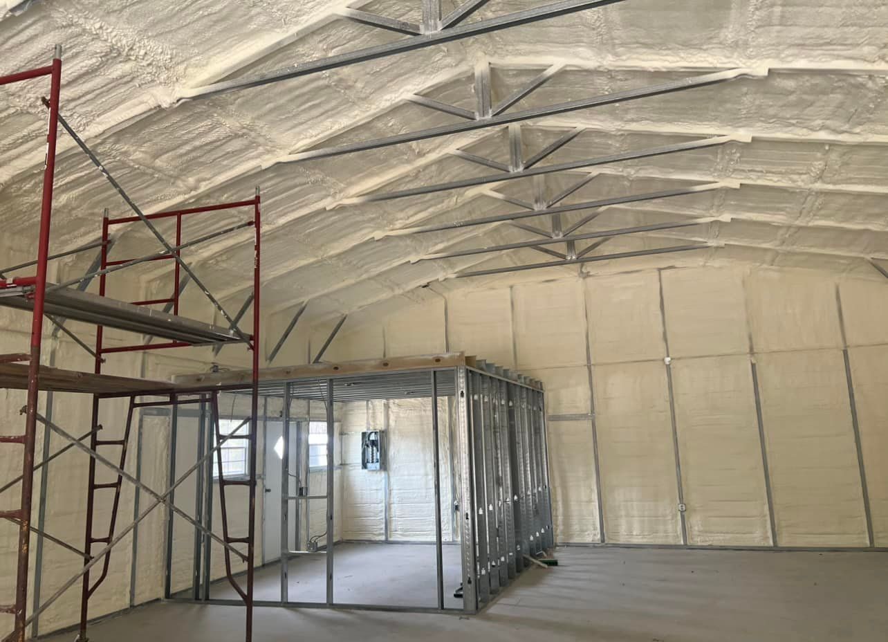 Interior of a building insulated with white spray foam. Scaffolding and metal framing are visible.