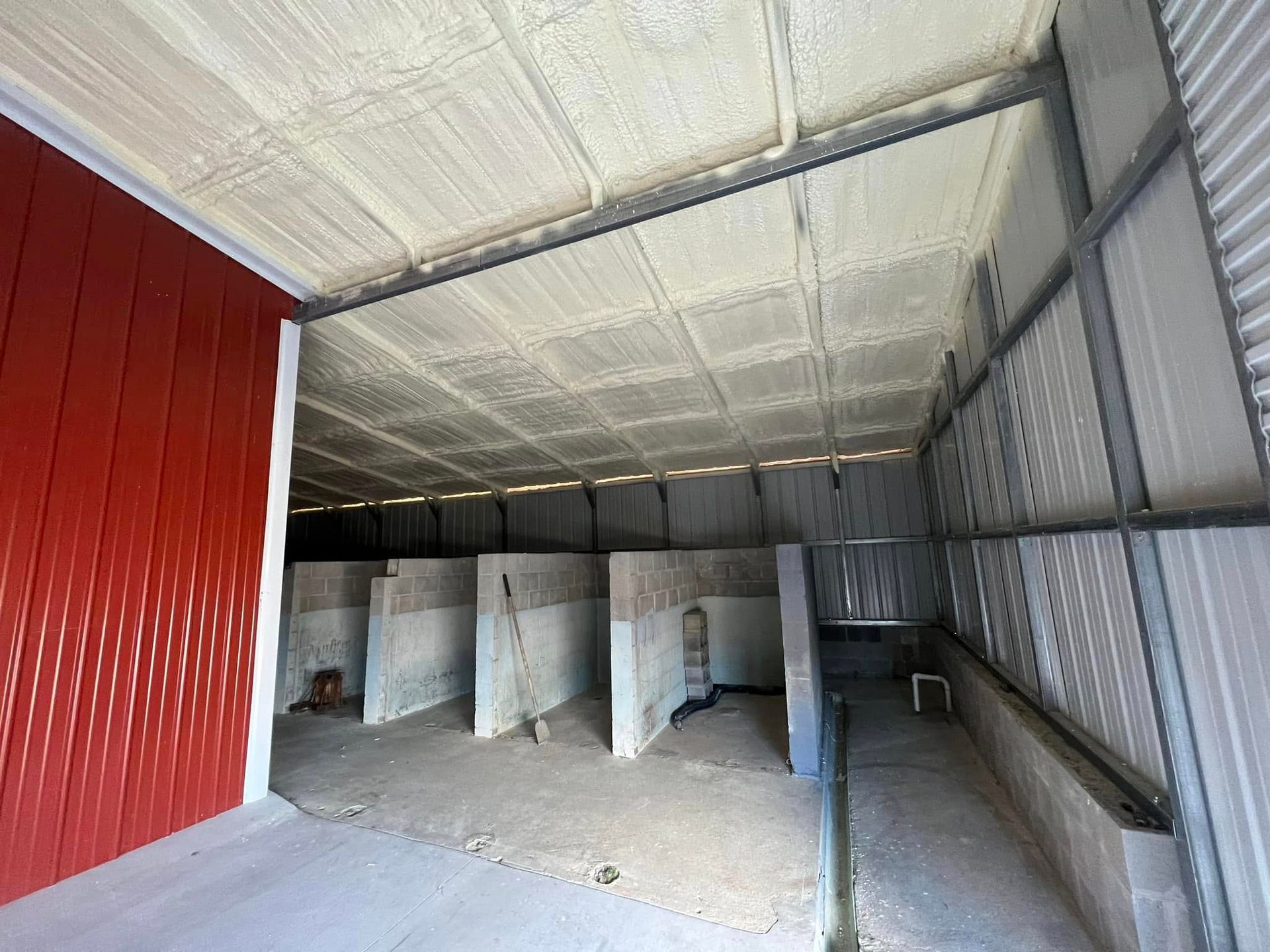 Interior view of a building with spray foam insulation on the ceiling and red walls.