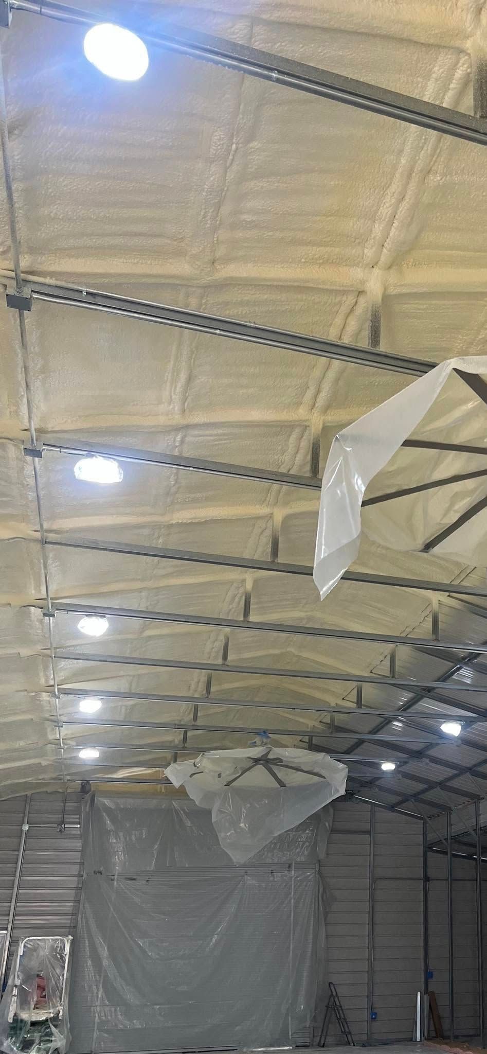 Interior of a warehouse with a high, insulated ceiling, lighting, and a large object covered with plastic.