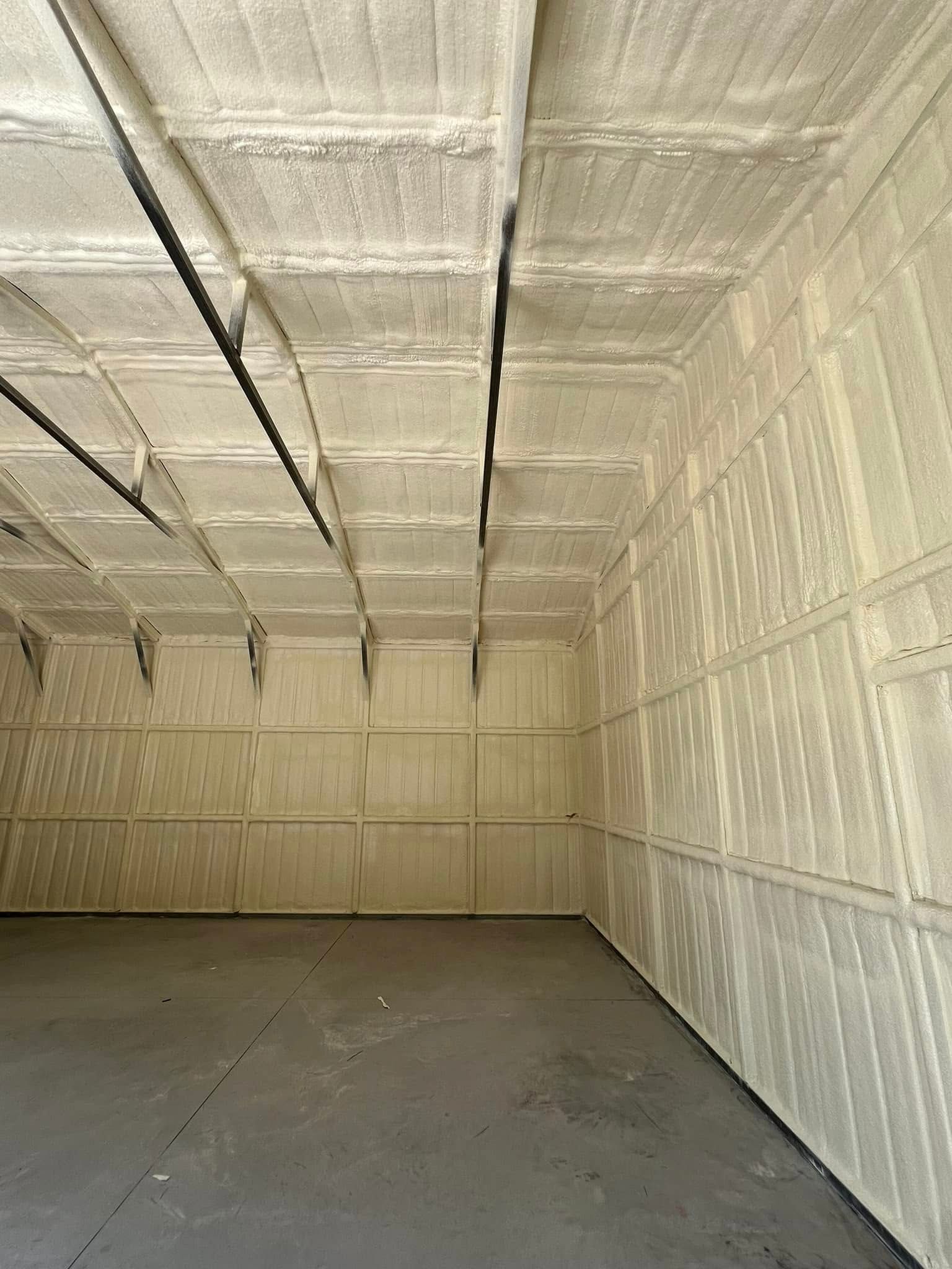 Interior of a building with spray foam insulation on the walls and ceiling. Gray concrete floor.