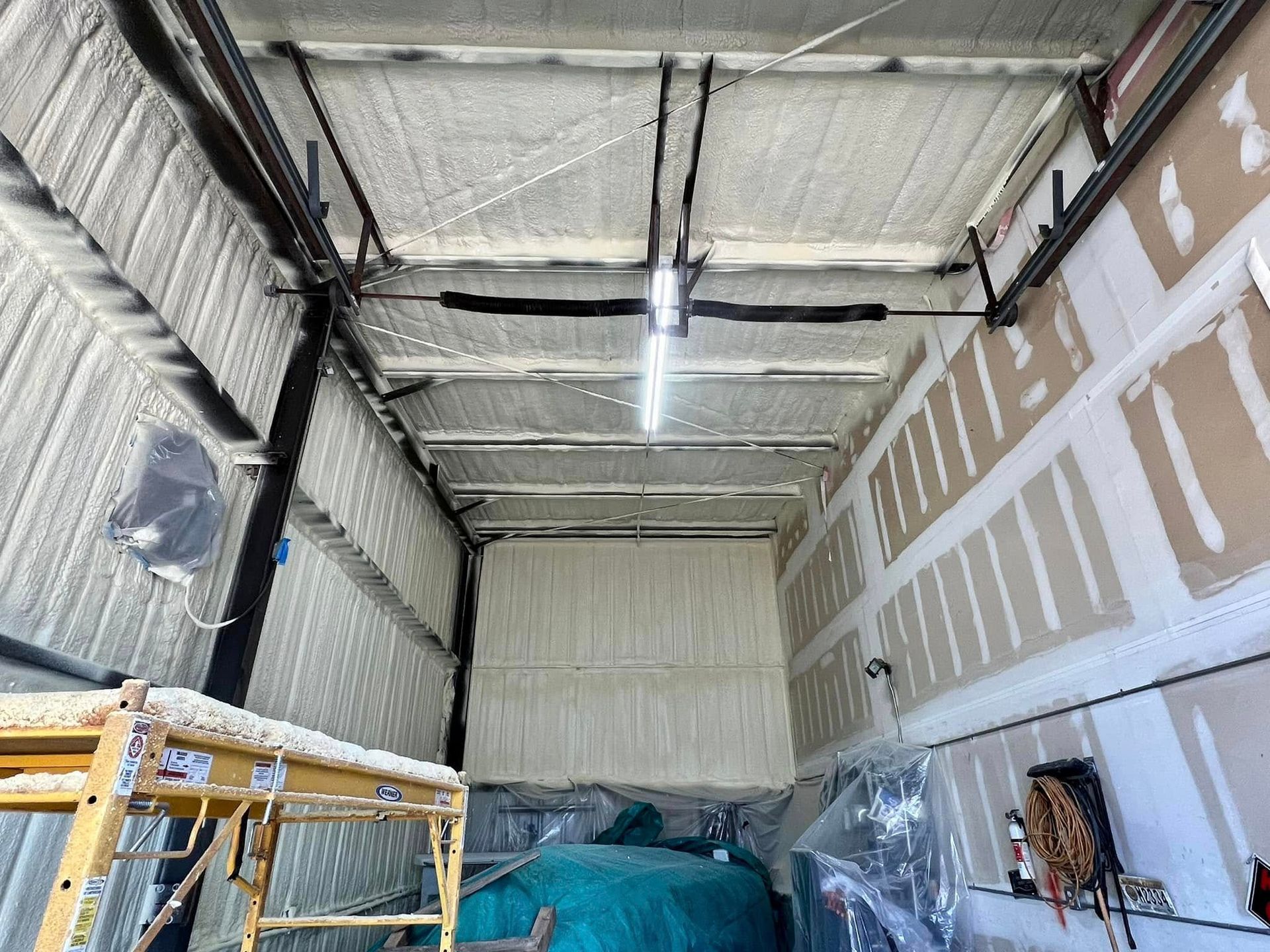 Garage interior with spray foam insulation on walls and ceiling.