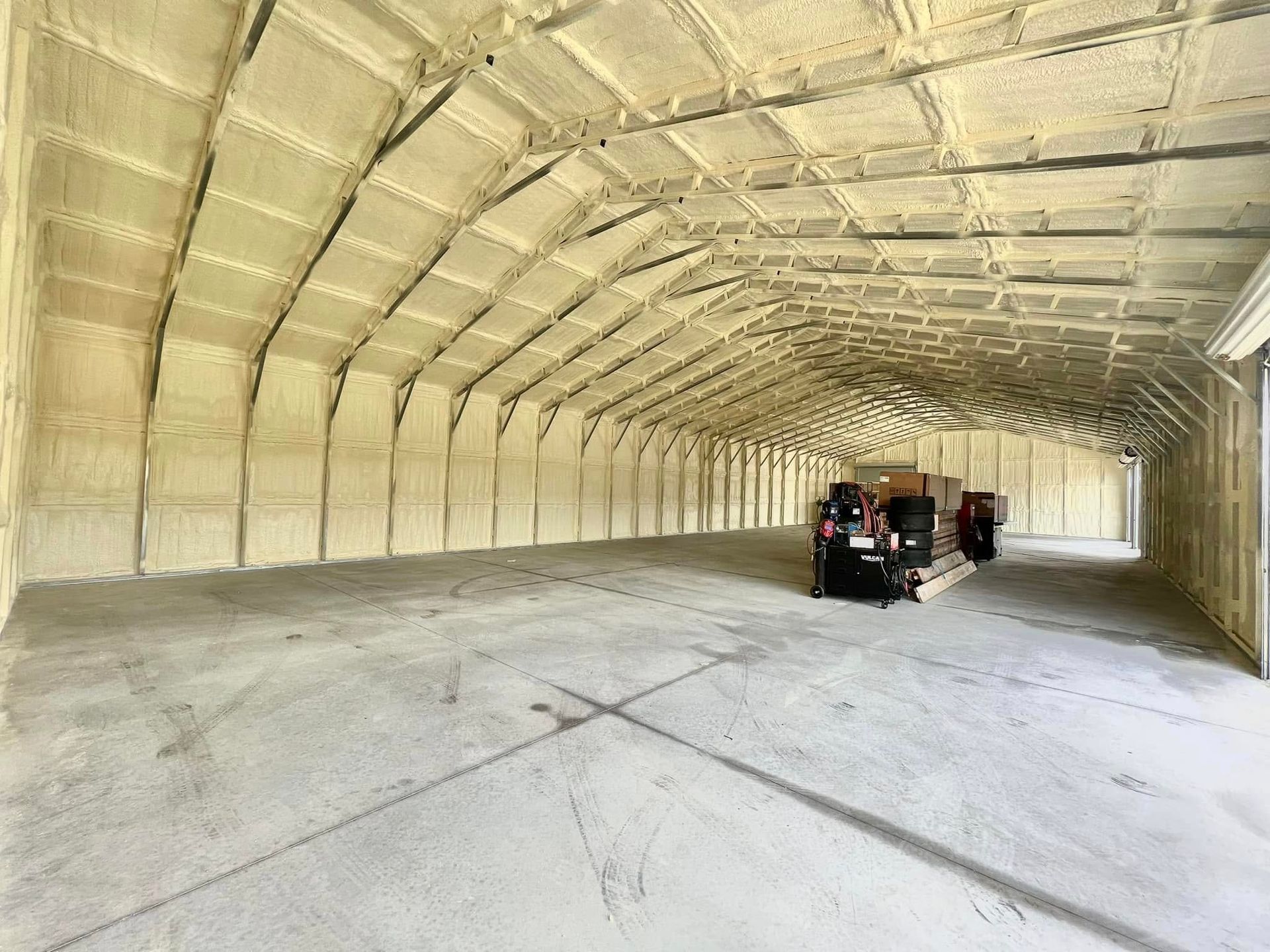 Interior view of a large warehouse insulated with spray foam on walls and ceiling; concrete floor.