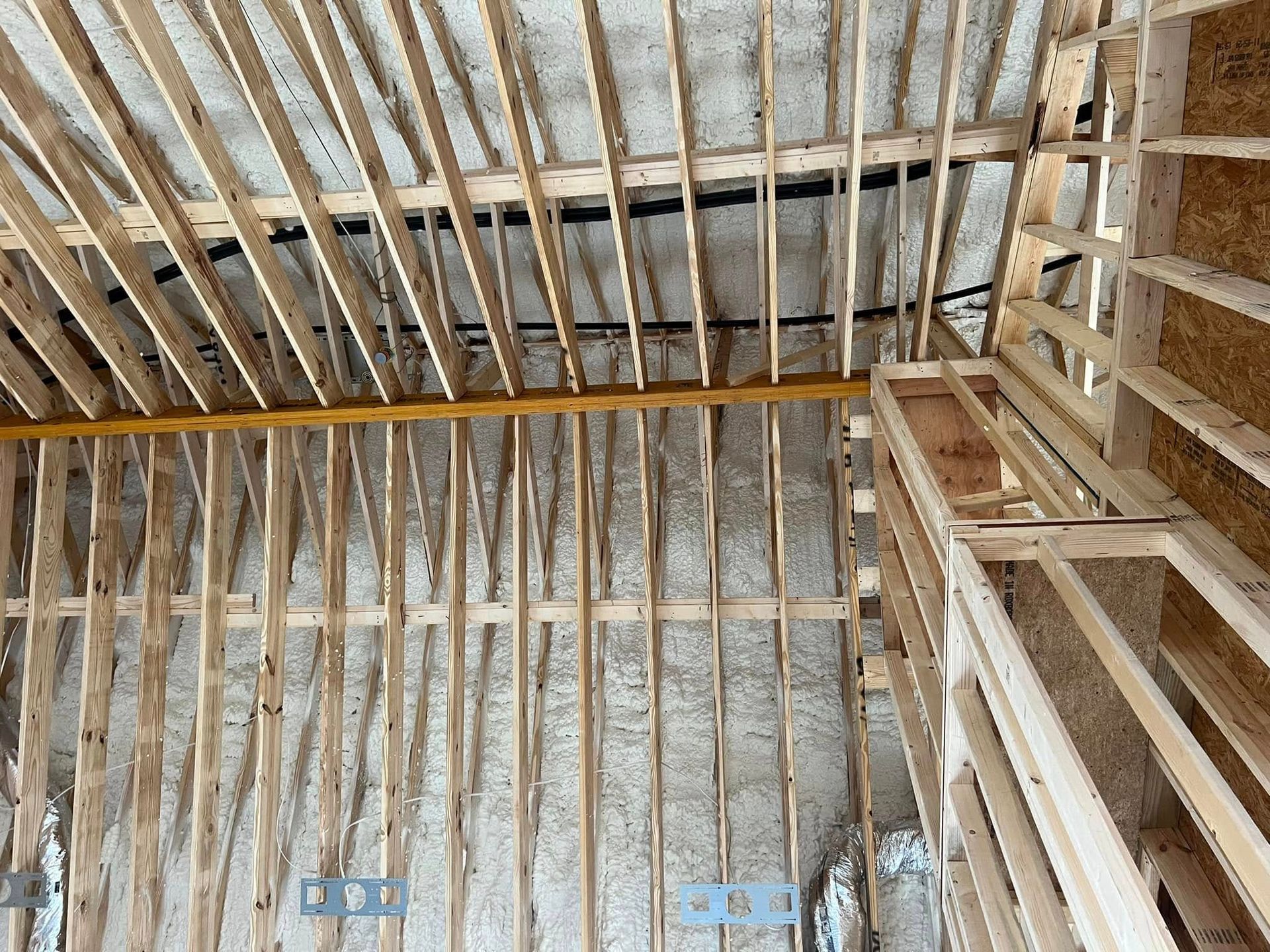 Interior view of a building under construction, showing wooden framing and insulation.