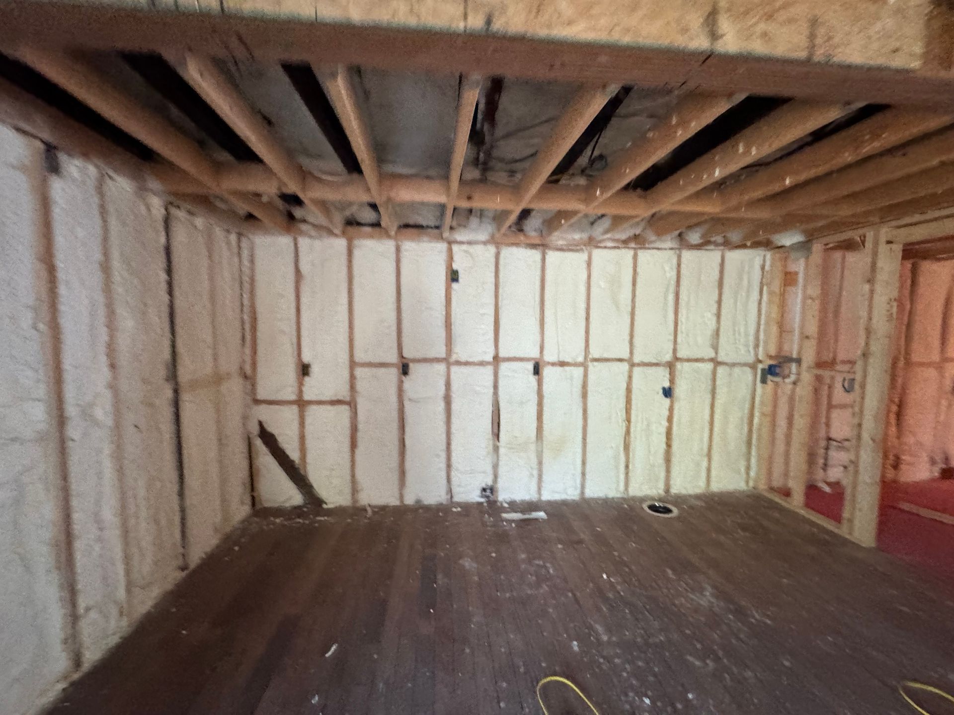 Interior room with exposed framing and walls insulated with white foam.