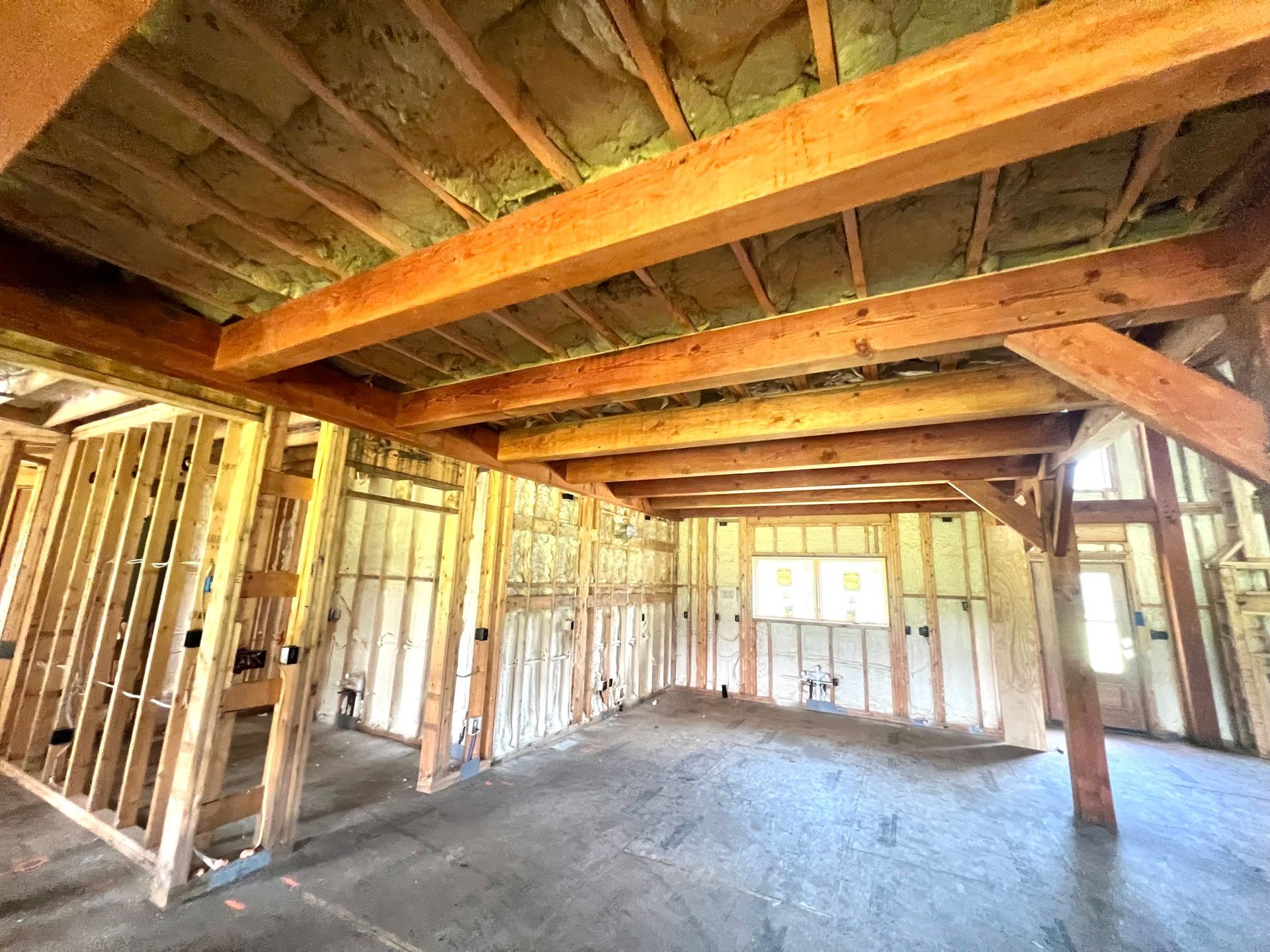 Interior of a building under construction, wooden framework, exposed beams and insulation, unfinished walls.