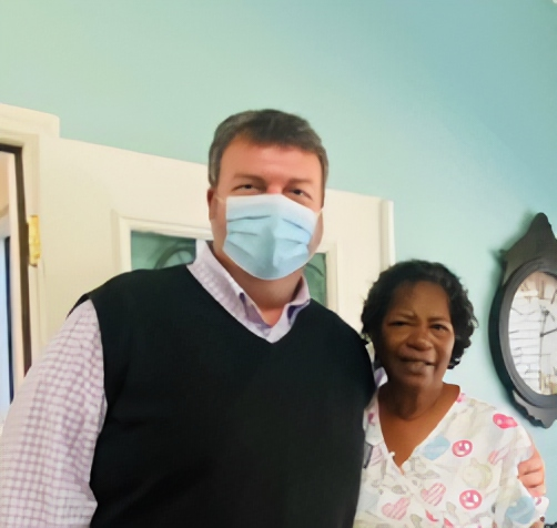 A man wearing a mask stands next to a woman