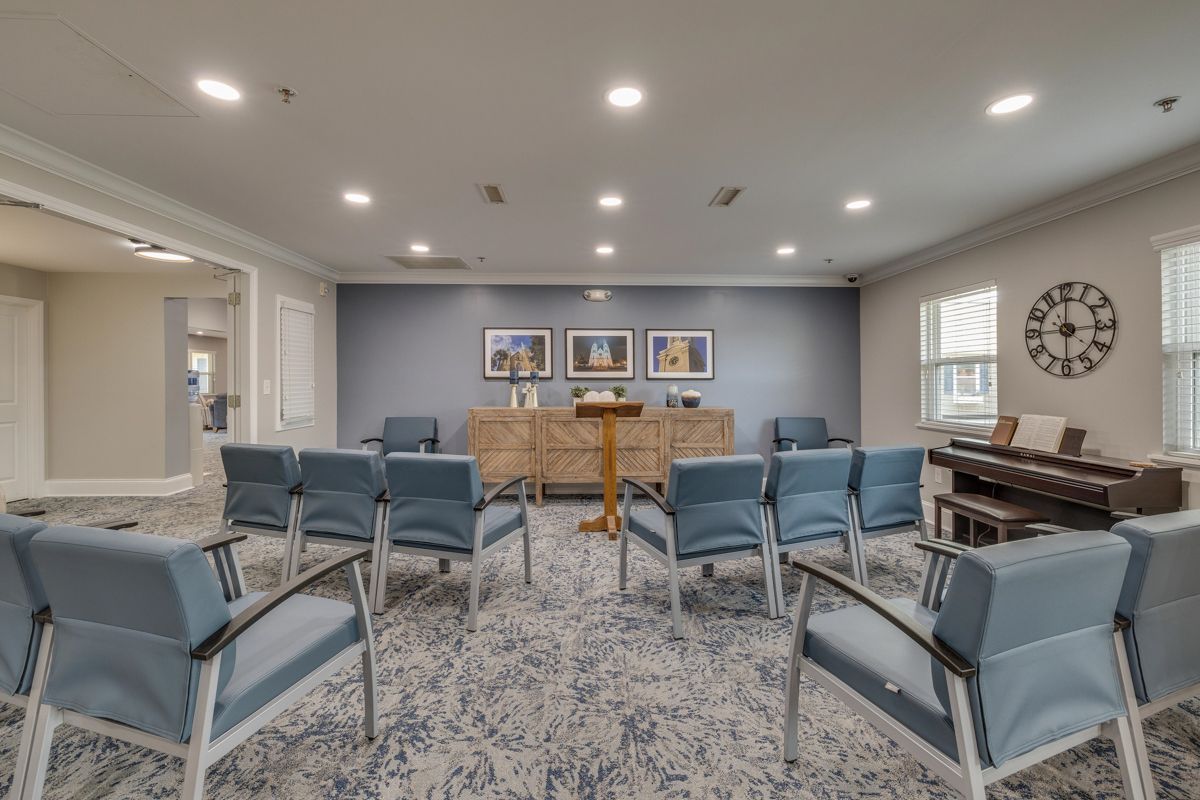 A room filled with chairs and a piano with a clock on the wall.