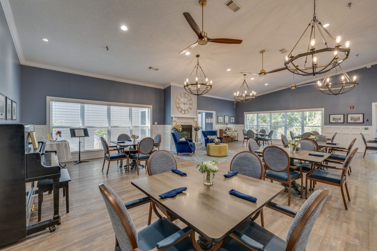 A large dining room with tables and chairs and a piano.
