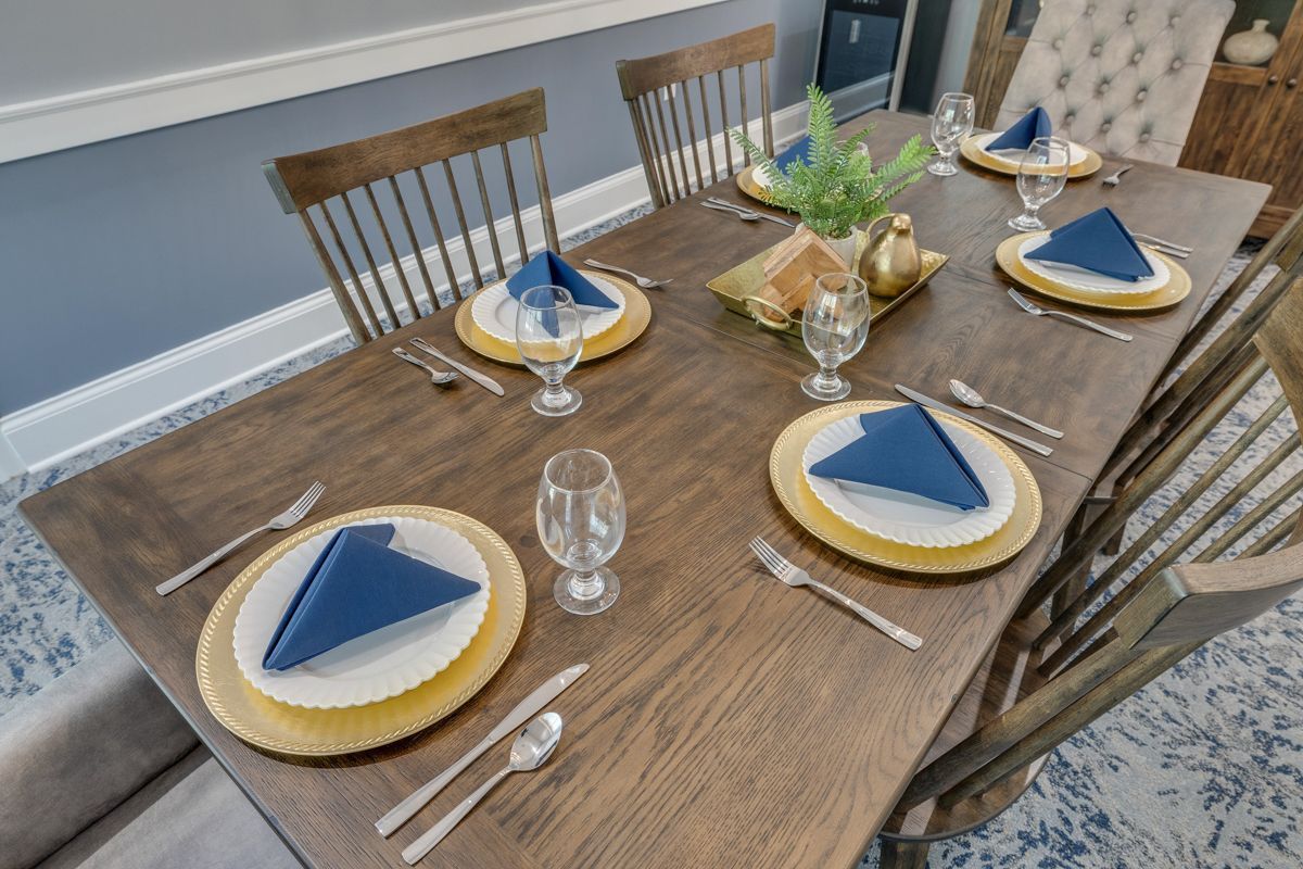 A dining room table with plates , silverware , and napkins on it.
